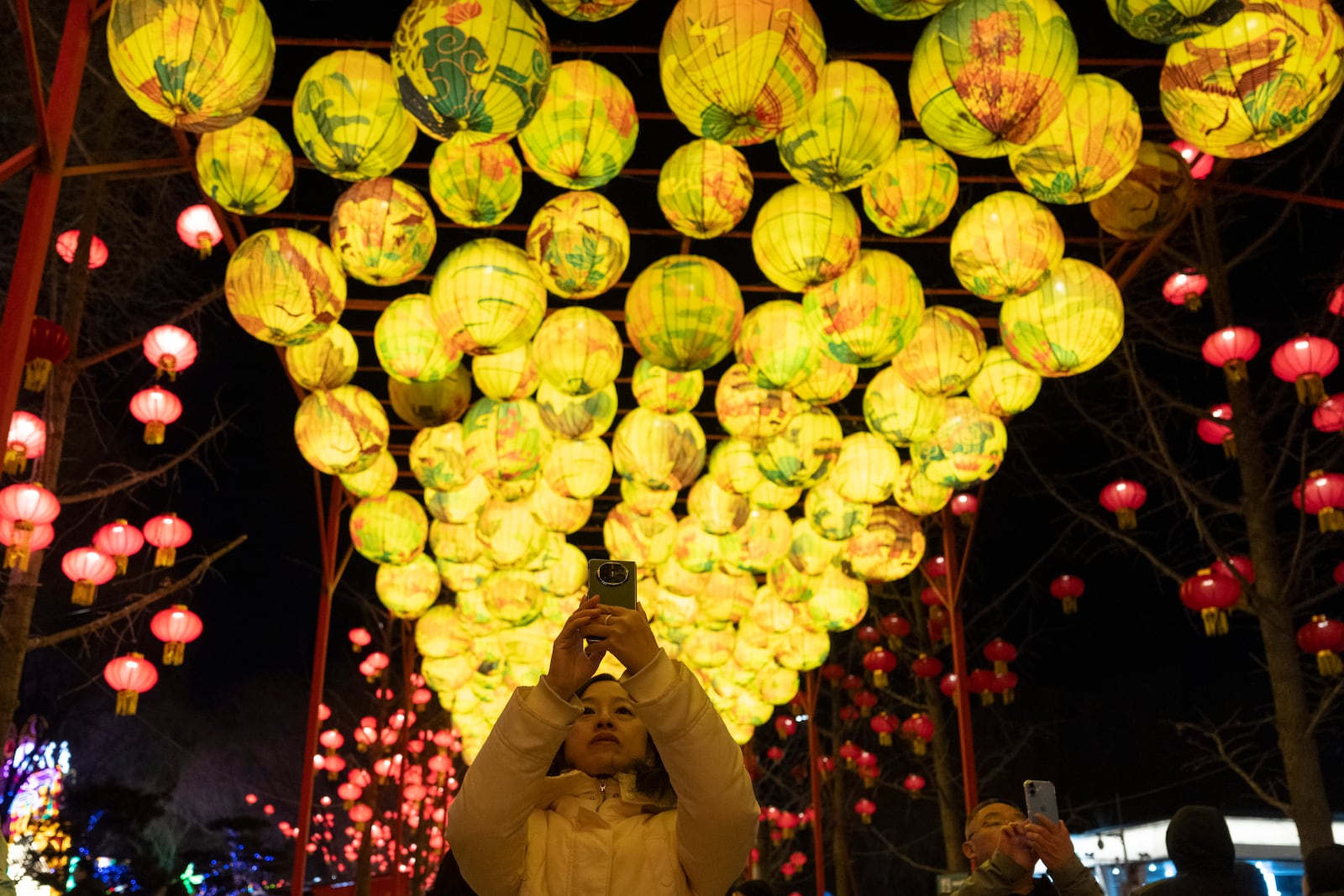 A woman takes photos near lanterns at the Lantern Festival during Yuanxiao, the fifteen day of the Lunar New Year in Beijing, Wednesday, Feb. 12, 2025. (AP Photo/Ng Han Guan)