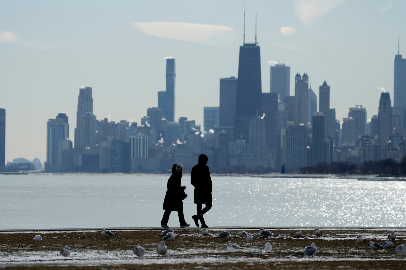 Pedestrians bundle up as they walk along the shore of Lake Michigan at Montrose beach during cold weather in Chicago, Wednesday, Jan. 8, 2025. (AP Photo/Nam Y. Huh)