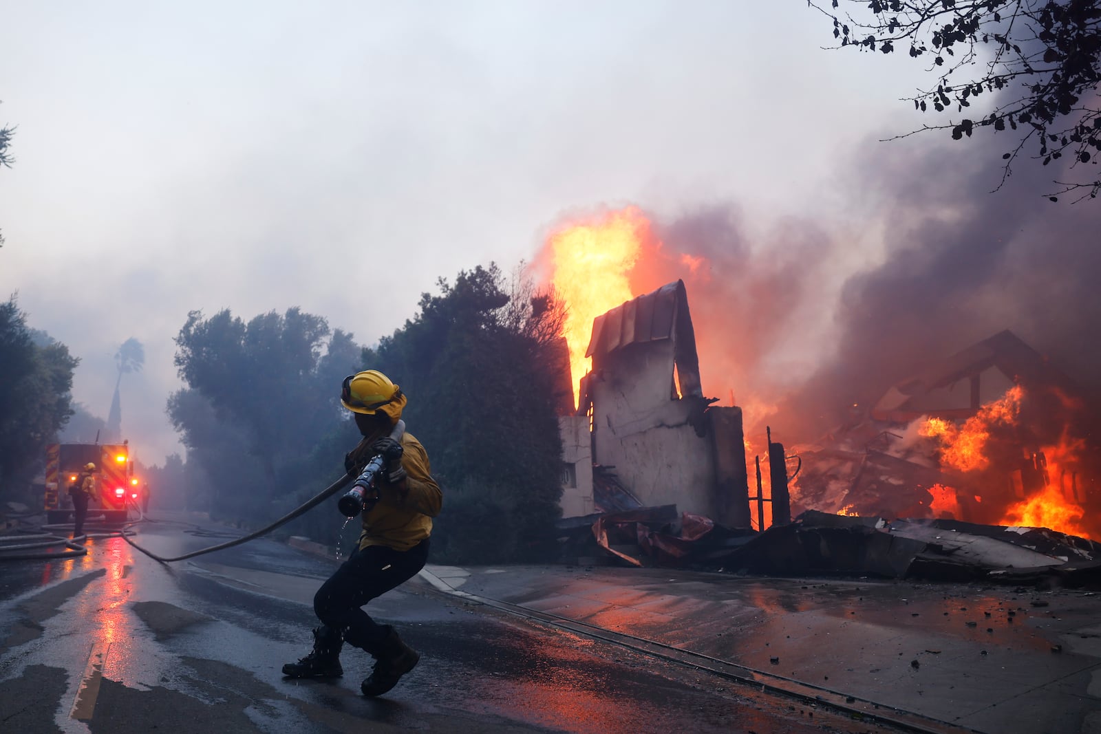 A firefighter battles the advancing Palisades Fire as it burns a structure in the Pacific Palisades neighborhood of Los Angeles, Tuesday, Jan. 7, 2025. (AP Photo/Etienne Laurent)