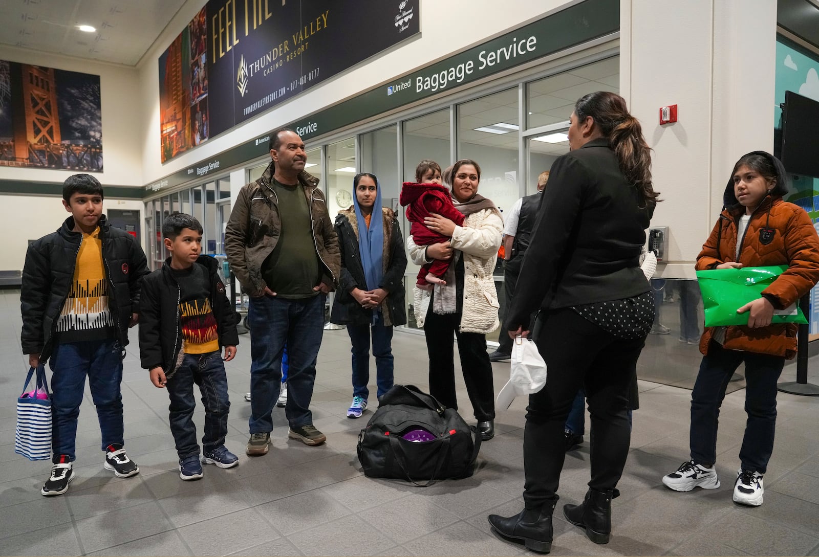 After leaving Afghanistan two-months earlier, Mohammad Saboor Osmani, third from left, and his family are greeted by a representative of No One left Behind Organization after their arrival at the Sacramento International Airport in Sacramento, Calif., Tuesday, March 11, 2025. (AP Photo/Rich Pedroncelli).