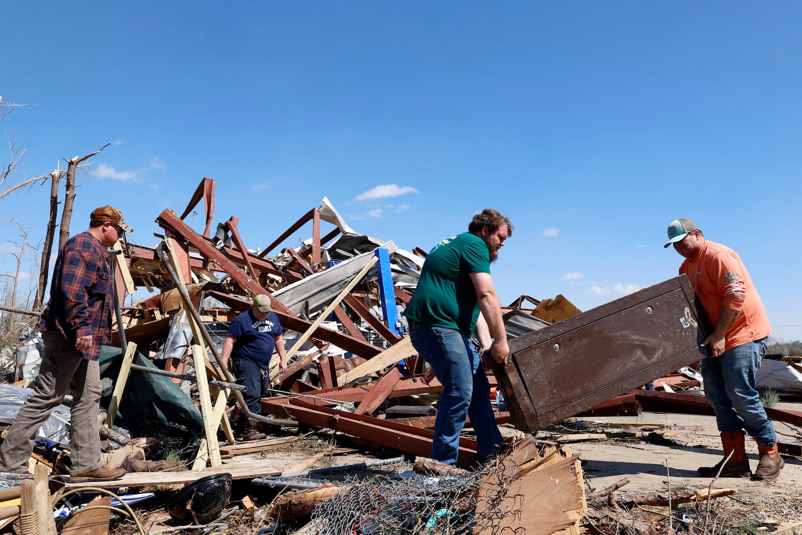 Friends and family carry off a safe from the damaged building after a tornado passed through the area, Sunday, March 16, 2025, in Plantersville, Ala. (AP Photo/Butch Dill)