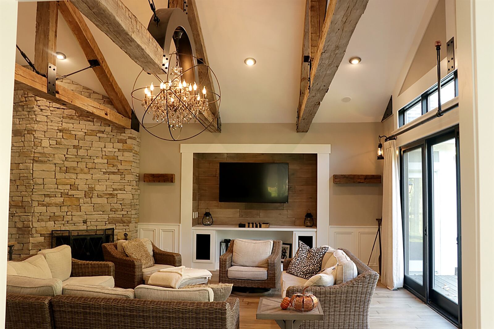 Peaking above the great room is a custom chandelier with crystal accents within a wrought-iron sphere. The cross beam from which the light hangs was reinforced with black iron joists and connectors. A wall was opened to allow panoramic views of the tree-lined back yard. CONTRIBUTED PHOTO BY KATHY TYLER