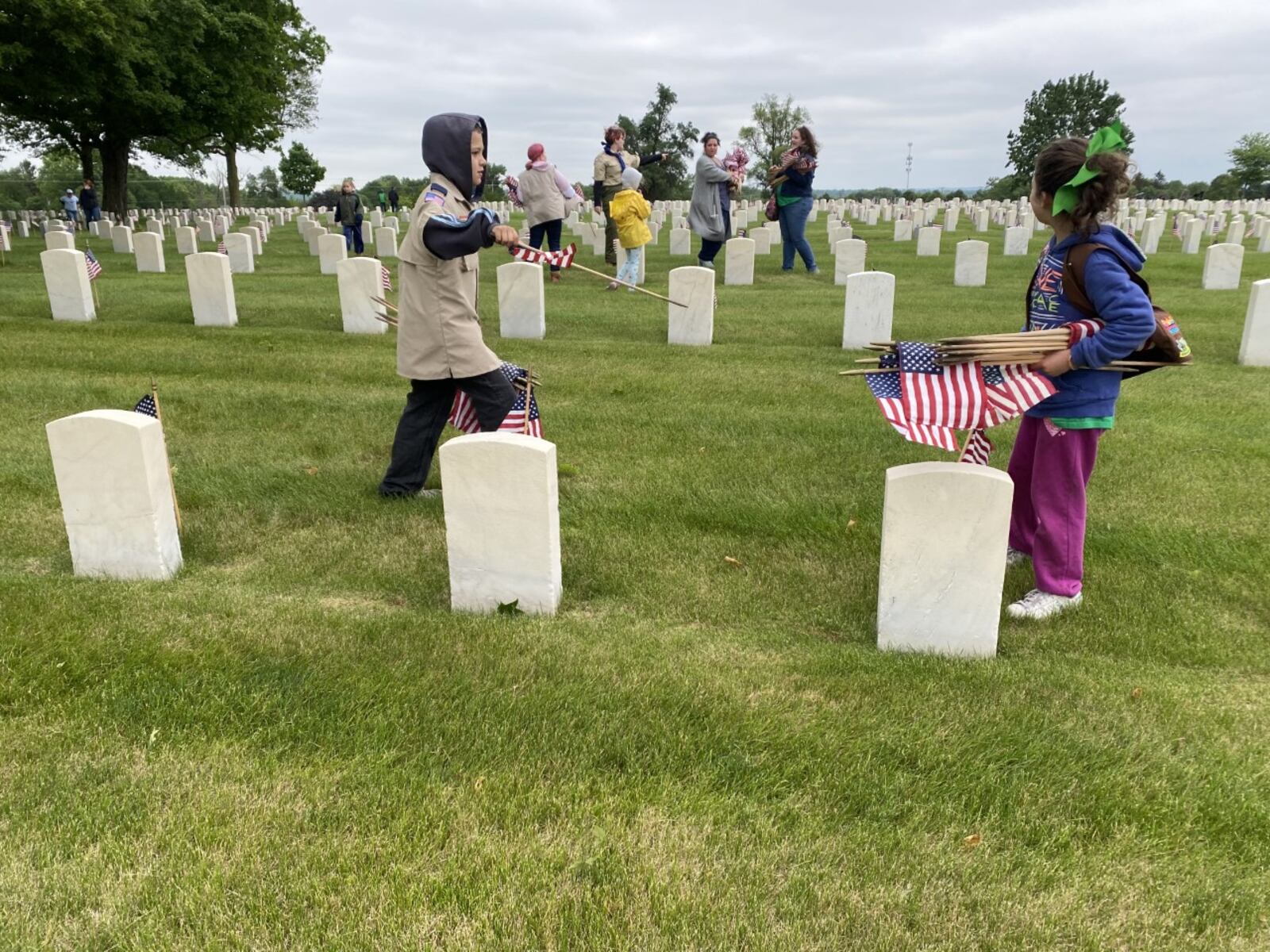 Jeffrey Baylor, 10, of Cub Pack 402, and Lily Baylor, 8, of Girl Scout Troop 35155, place flags on veterans' graves on Saturday, May 29. Eileen McClory / Staff