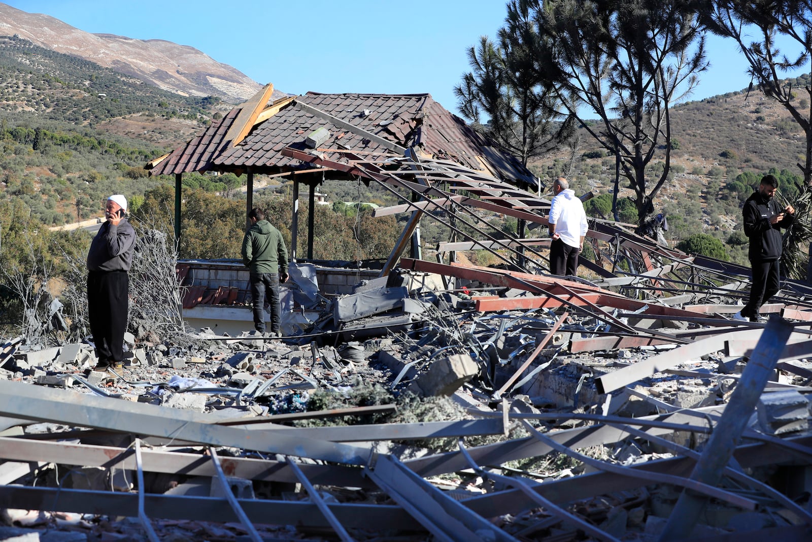 People observe the site where an Israeli airstrike hit a compound housing journalists, killing three media staffers from two different news agencies according to Lebanon's state-run National News Agency, in Hasbaya village, southeast Lebanon, Friday, Oct. 25, 2024. (AP Photo/Mohammed Zaatari)