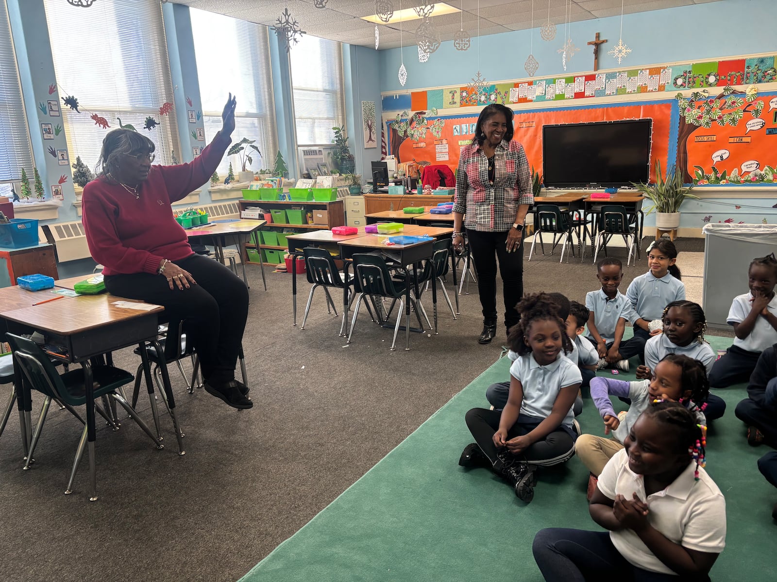 Debby Wright, a substitute teacher for St. Benedict the Moor Catholic School, plays a game with the first grade class while principal Caroyln Day, right, looks on. Eileen  McClory / staff