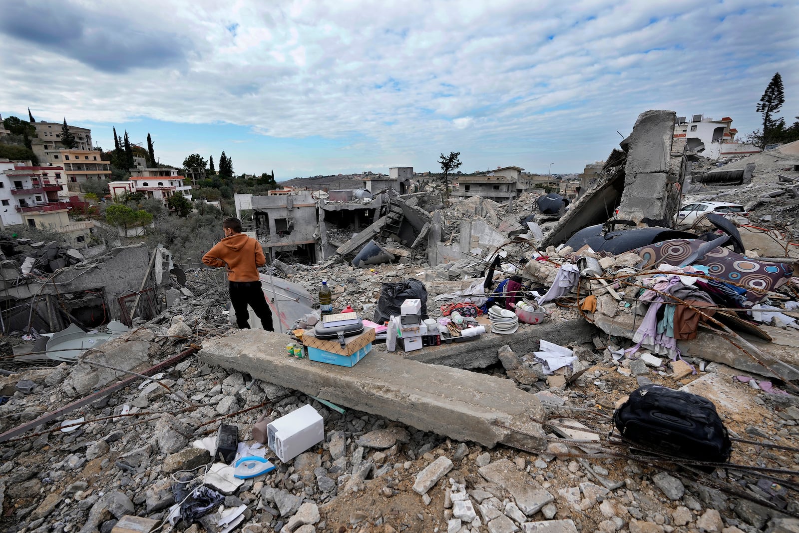 A person stands next to remains and his family destroyed house after he returned to Chehabiyeh village, southern Lebanon, Thursday, Nov. 28, 2024 following a ceasefire between Israel and Hezbollah that went into effect on Wednesday. (AP Photo/Hussein Malla)