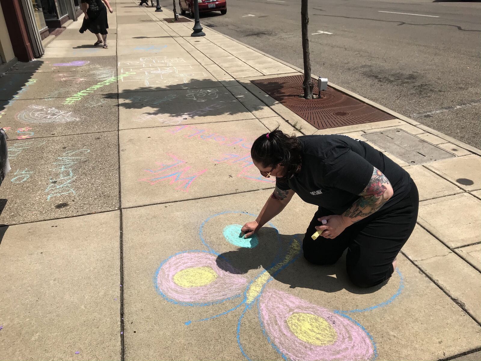 Erica Stevel paints with chalk the sidewalk on Main Street in Fairborn to get ready for a protester scheduled to begin at 3 p.m. STAFF PHOTO / JIM NOELKER