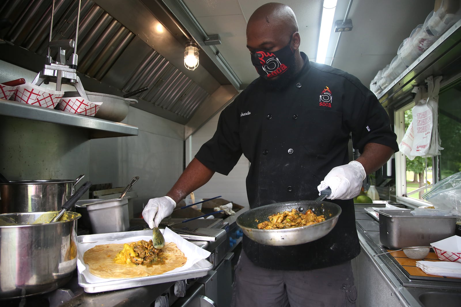 Ricardo Modeste, co-owner of the Soca food truck, creates a dish. LISA POWELL / STAFF