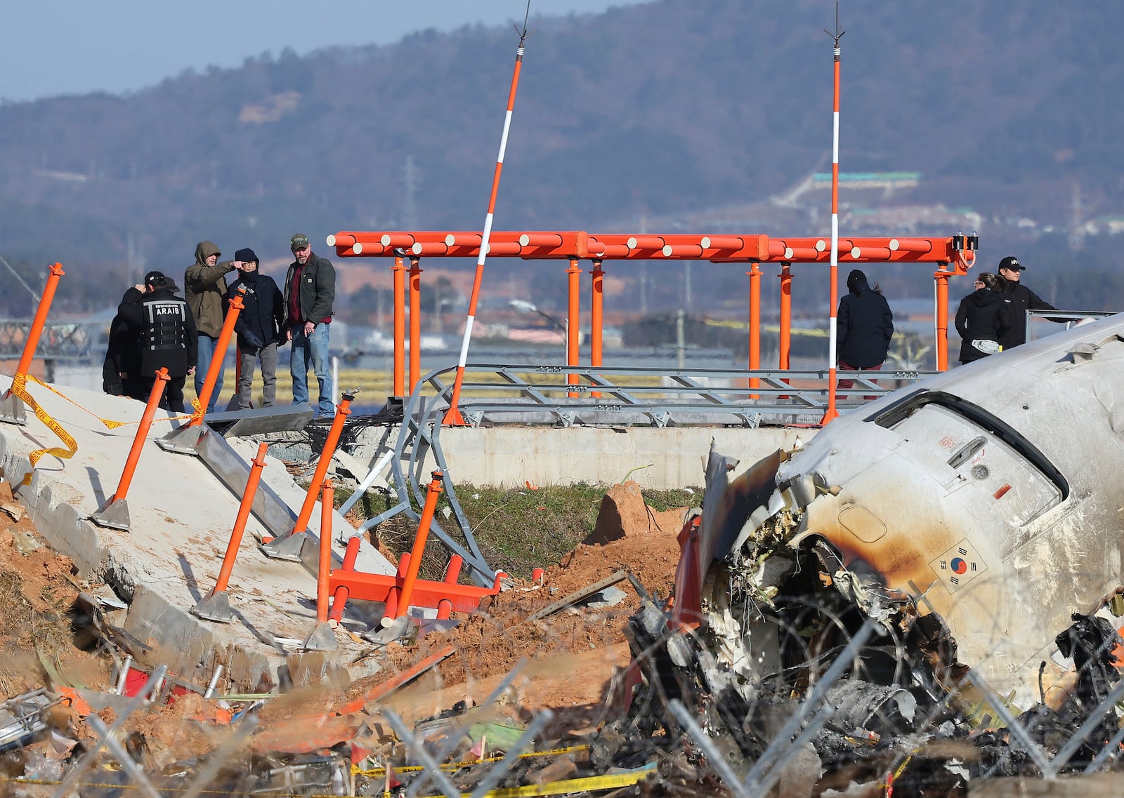 Experts from the U.S. National Transportation Safety Board (NTSB) and joint investigation team between the U.S. and South Korea check the site of a plane crash at Muan International Airport in Muan, South Korea, Tuesday, Dec. 31, 2024. (Son Hyung-joo/Yonhap via AP)