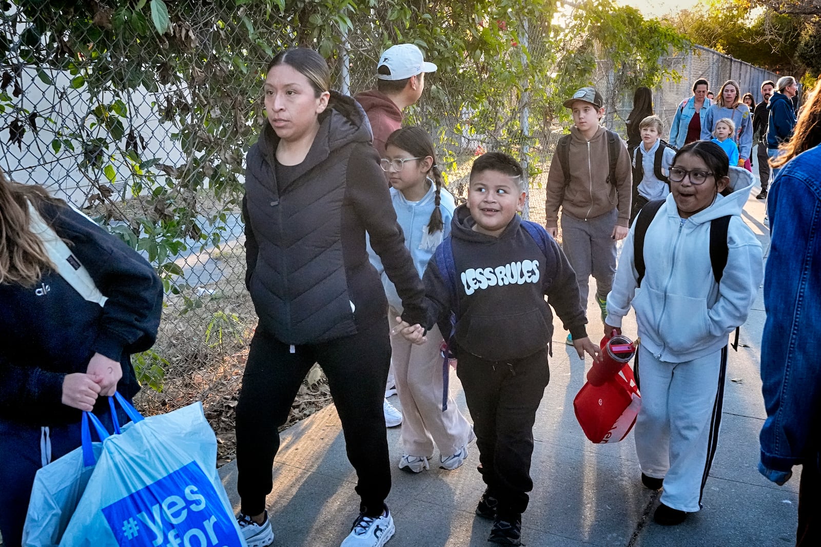 Palisades Charter Elementary School students and their parents arrive at their new school, the Brentwood Elementary Science Magnet school in the Brentwood section of Los Angeles on Wednesday, Jan. 15, 2025. (AP Photo/Richard Vogel)