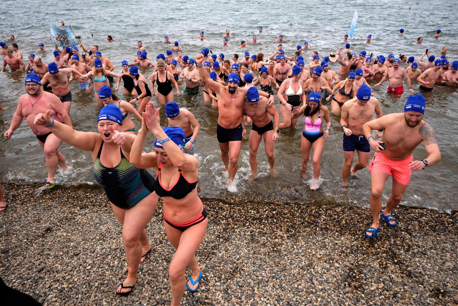 Some of 2461 polar swimmers get out of the water after breaking a world record for the largest polar bear dip at a lake in Most, Czech Republic, Saturday, March 1, 2025. (AP Photo/Petr David Josek)