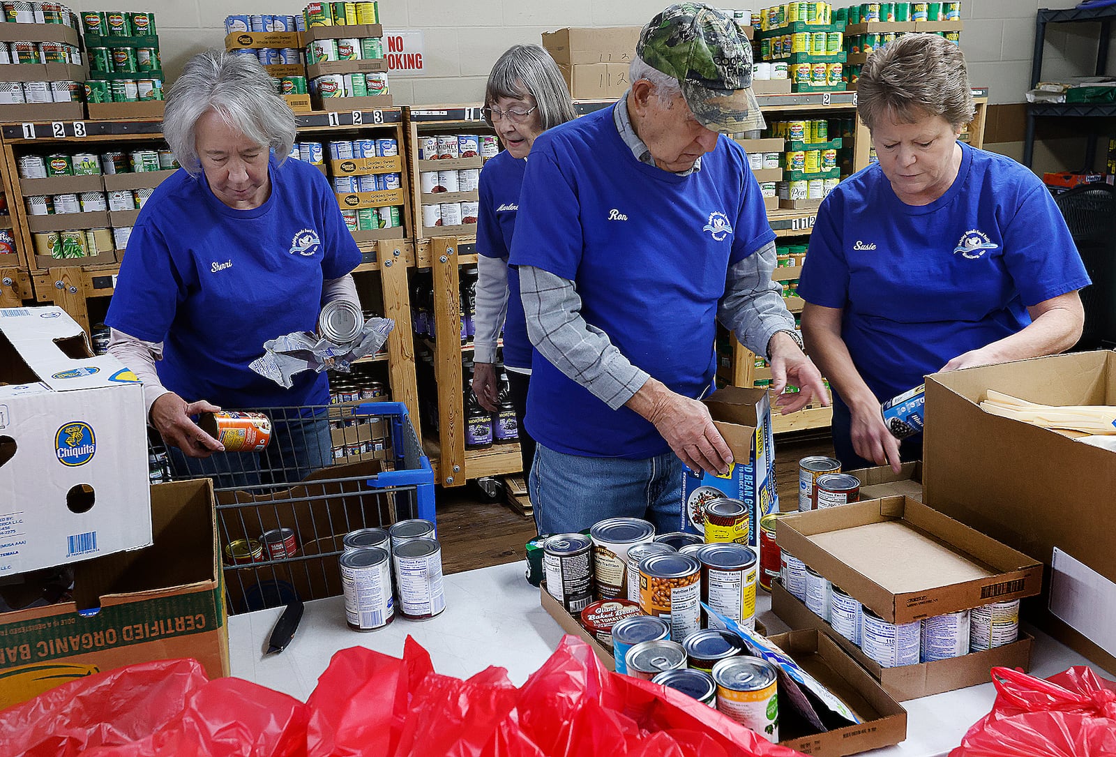 Miamisburg Helping Hands Food Pantry volunteers, from left, Sherrie Iddings, Marlene Schmitz, Ron Schmitz and Susie Huffman sort cans of food, Wednesday, Feb. 12, 2025. The nonprofit organization got its start on Feb. 17, 1965. MARSHALL GORBY/STAFF