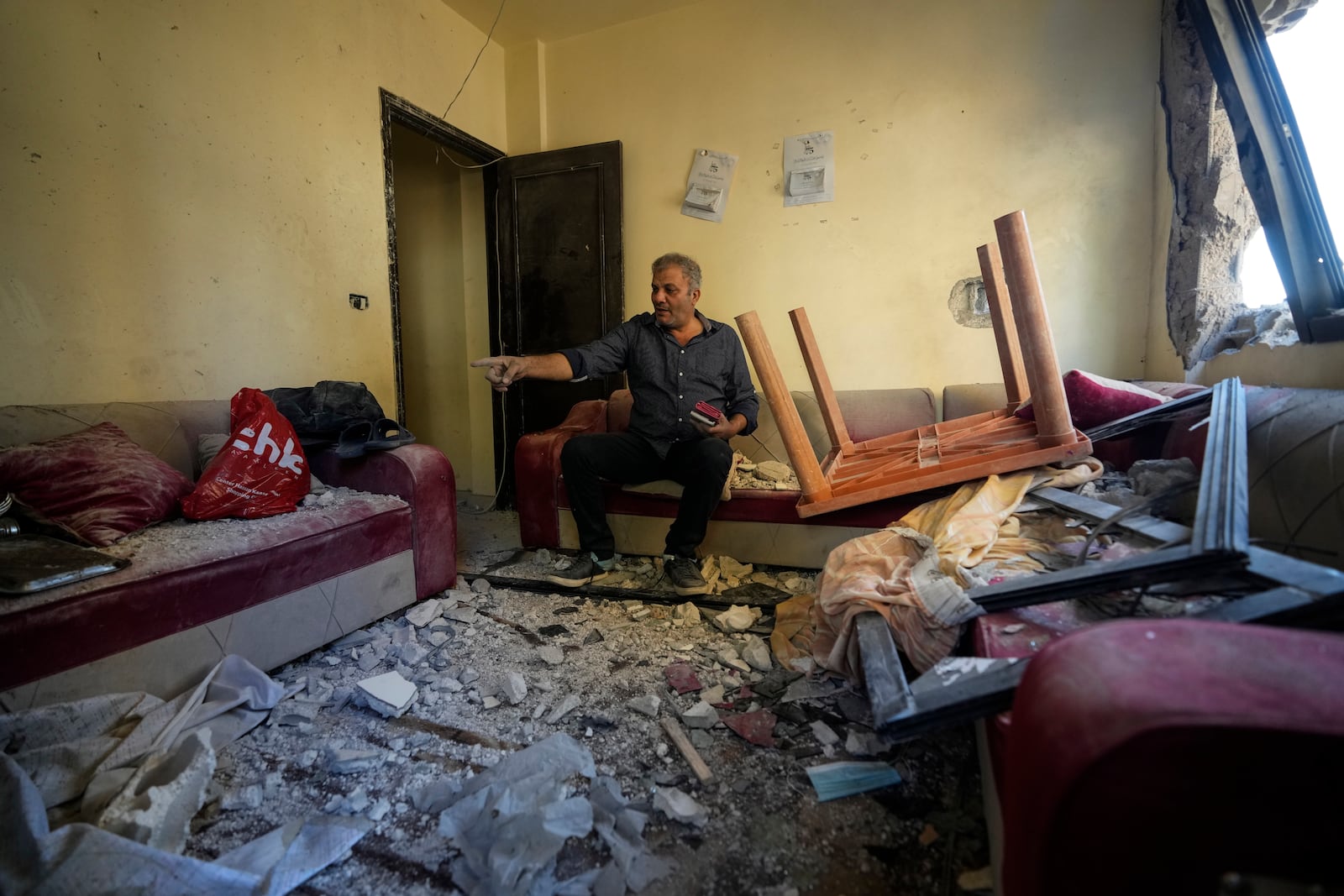 An injured resident sits in his damaged house after an Israeli airstrike hit a building on Tuesday night, in Barja, Lebanon, Wednesday, Nov. 6, 2024. (AP Photo/Hassan Ammar)