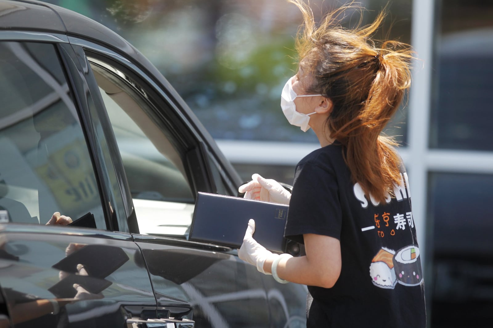 Hannah Huang, owner of Tokyo Sushi & Grill, delivers food to her new customers Tuesday afternoon across from Costco at Cornerstone of Centerville. The restaurant has been closed for weeks and Tuesday was the first day open to carryout. JIM NOELKER/STAFF