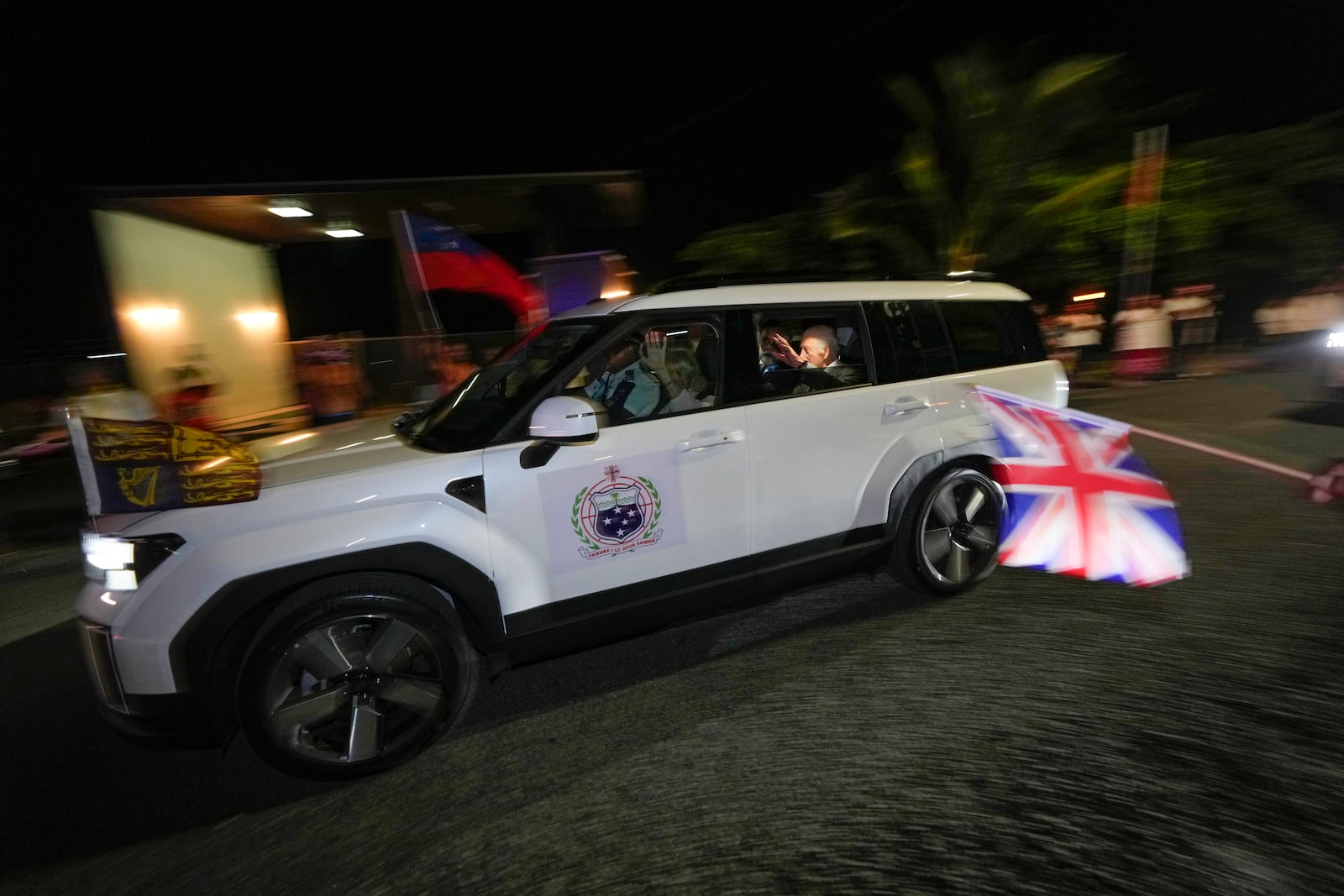 Britain's King Charles III and Queen Camilla wave as they arrive in the village of Siumu, Samoa, on Wednesday, Oct. 23, 2024. (AP Photo/Rick Rycroft)