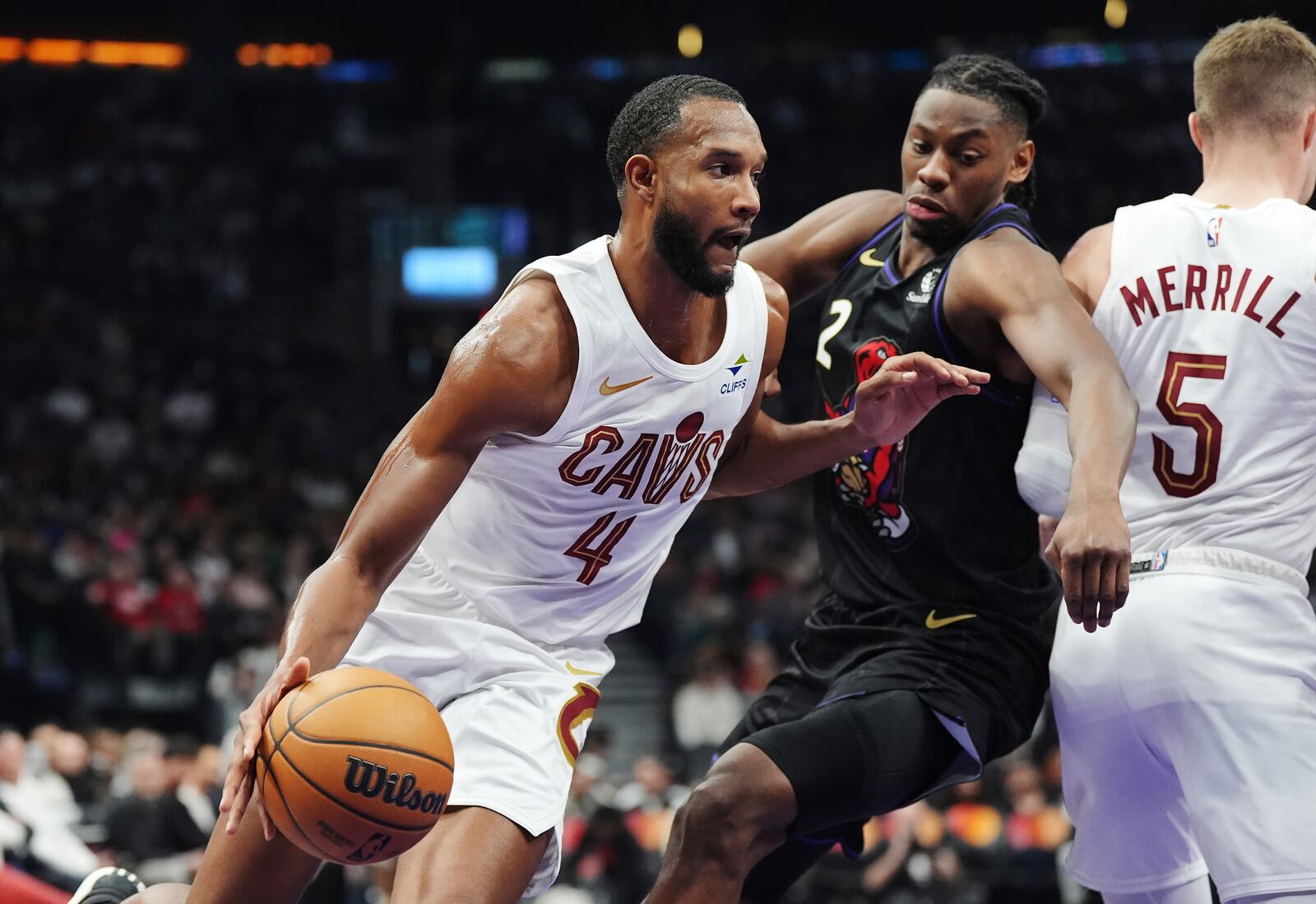 Cleveland Cavaliers' Evan Mobley (4) drives around Toronto Raptors' Jonathan Mogbo (2) during the first half of an NBA basketball game in Toronto, Wednesday, Feb. 12, 2025. (Frank Gunn/The Canadian Press via AP)