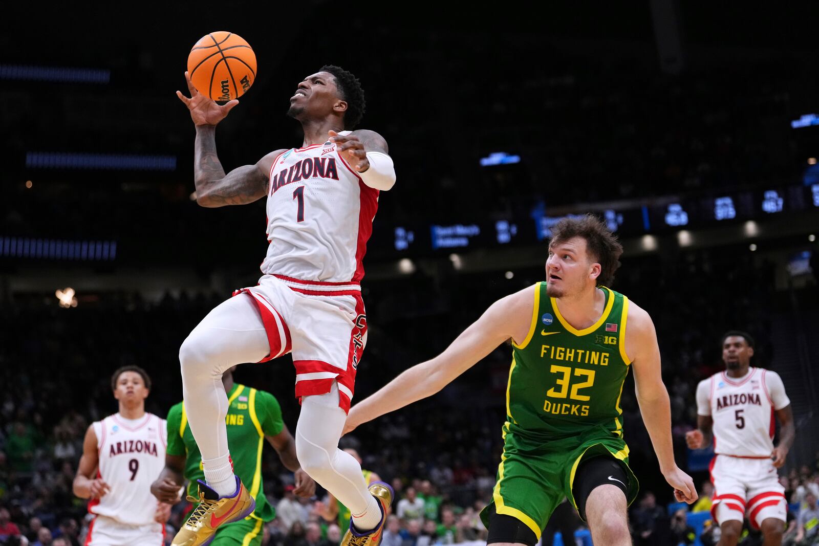 Arizona guard Caleb Love (1) moves to the basket against Oregon center Nate Bittle (32) during the second half in the second round of the NCAA college basketball tournament, Sunday, March 23, 2025 in Seattle. (AP Photo/Lindsey Wasson)