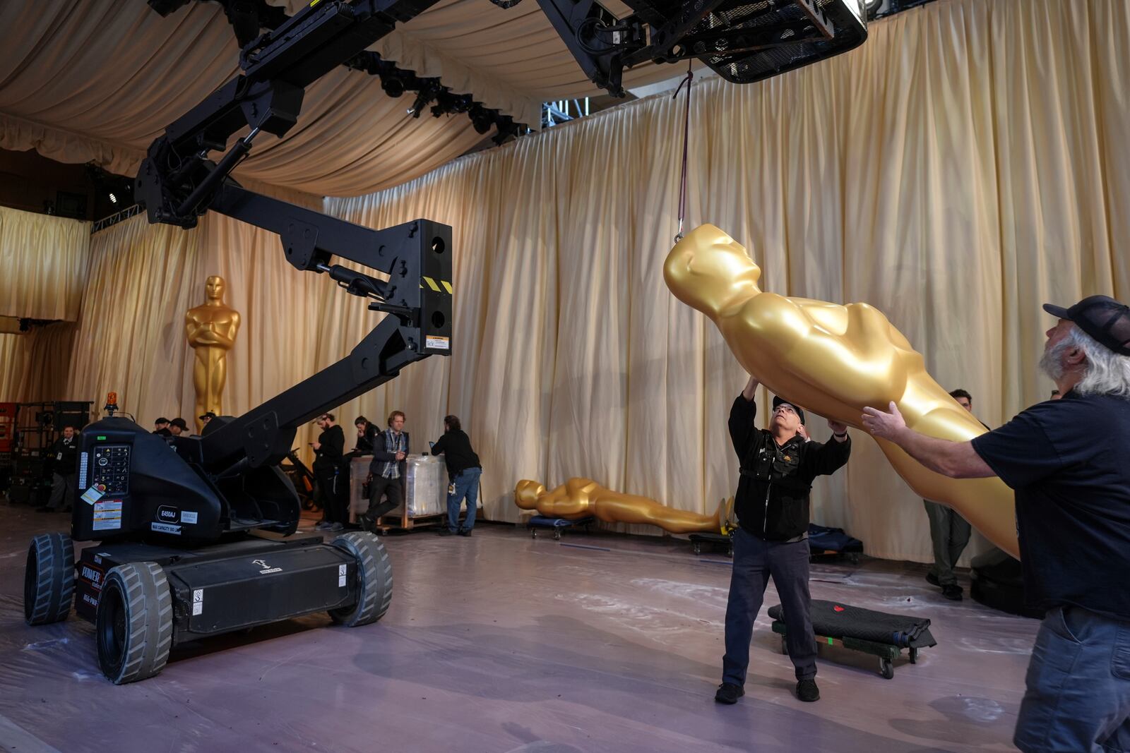 Workers set up an Oscar statue in the red carpet area before the 97th Academy Awards in Los Angeles, Saturday, March 1, 2025. (AP Photo/Jae C. Hong)