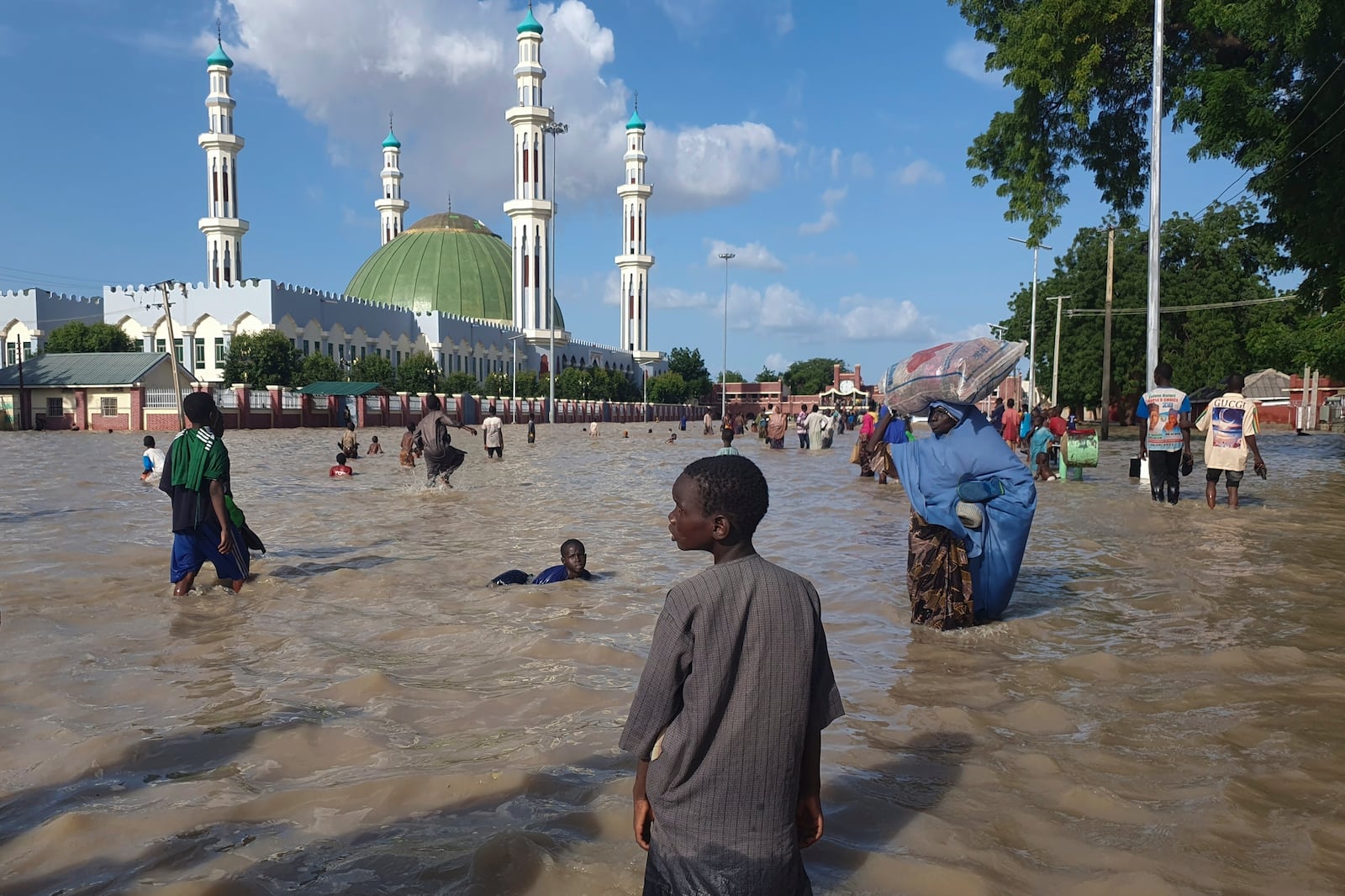 FILE - People walk through floodwaters following a dam collapse in Maiduguri, Nigeria, Sept 10, 2024. (AP Photos/ Joshua Olatunji, File)