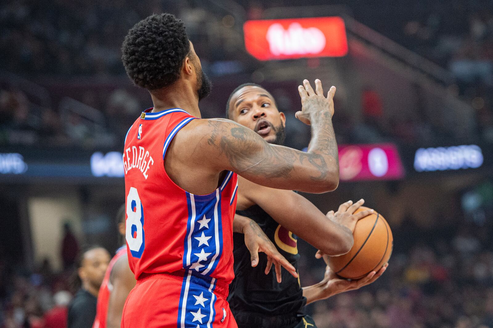 Philadelphia 76ers' Paul George (8) defends as Cleveland Cavaliers' Evan Mobley, rear looks to pass during the first half of an NBA basketball game in Cleveland, Saturday Dec. 21, 2024. (AP Photo/Phil Long)