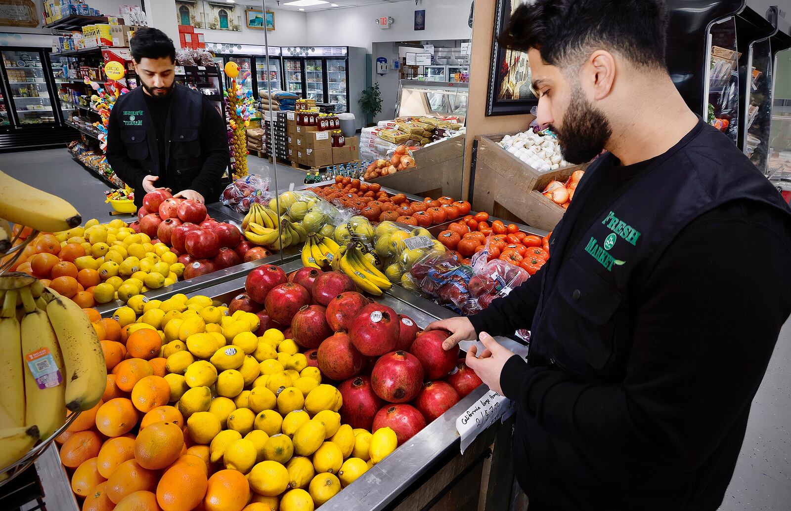 Muhajer "Amir" Almosawi, owner of the Fresh Halal Market straightens the fresh fruits and vegetables, Wednesday, Jan. 15, 2025. The market moved to a new location on Lyons Road in Washington Township. MARSHALL GORBY\STAFF