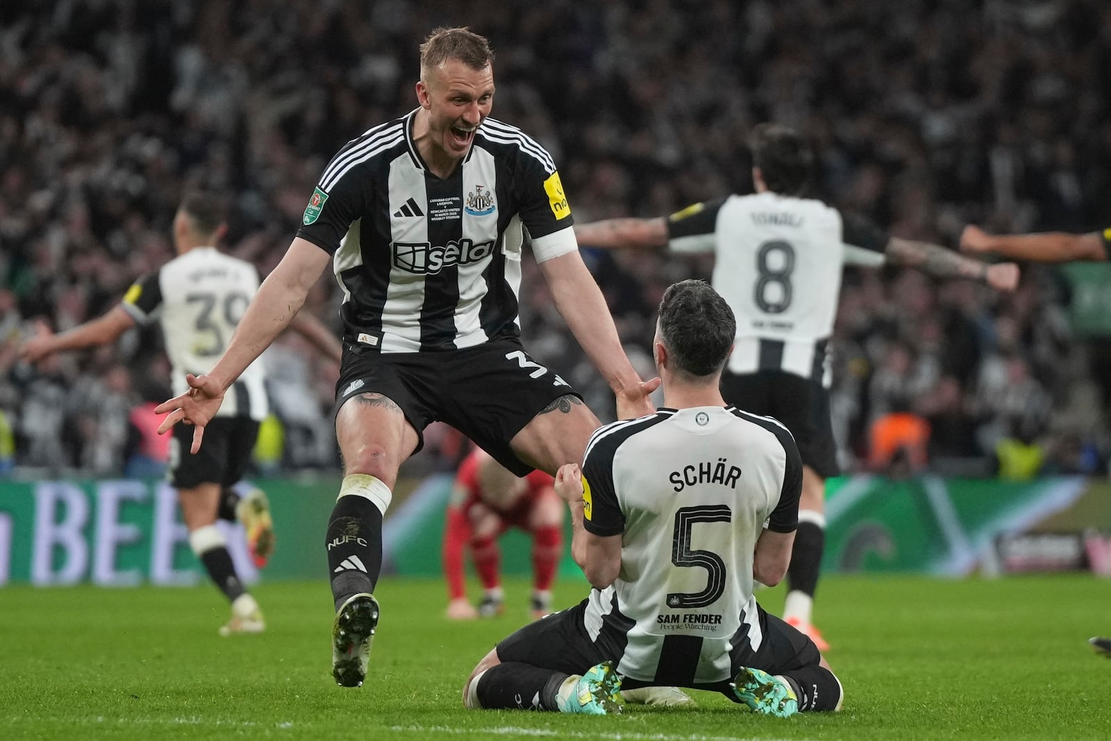 Newcastle's Dan Burn, left, and Newcastle's Fabian Schaer celebrate after winning the EFL Cup final soccer match between Liverpool and Newcastle at Wembley Stadium in London, Sunday, March 16, 2025. (AP Photo/Alastair Grant)