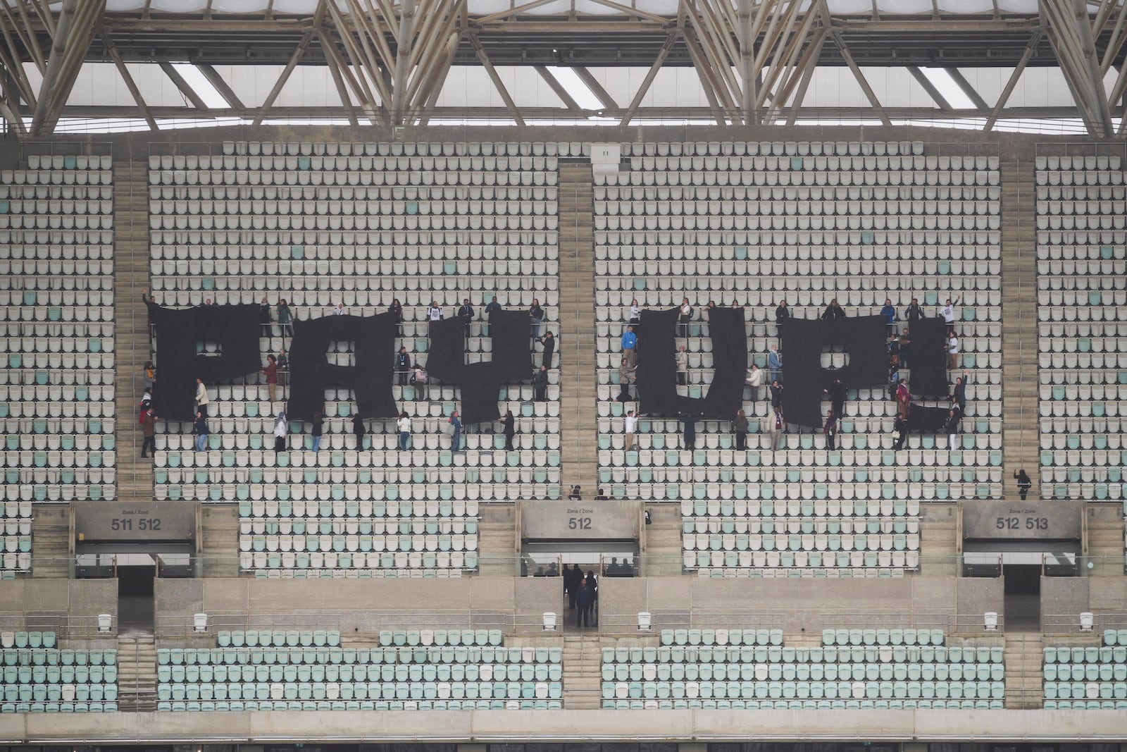 Activists with signs spell out "pay up" for climate finance in the Baku Olympic Stadium during the COP29 U.N. Climate Summit, Thursday, Nov. 14, 2024, in Baku, Azerbaijan. (AP Photo/Sergei Grits)