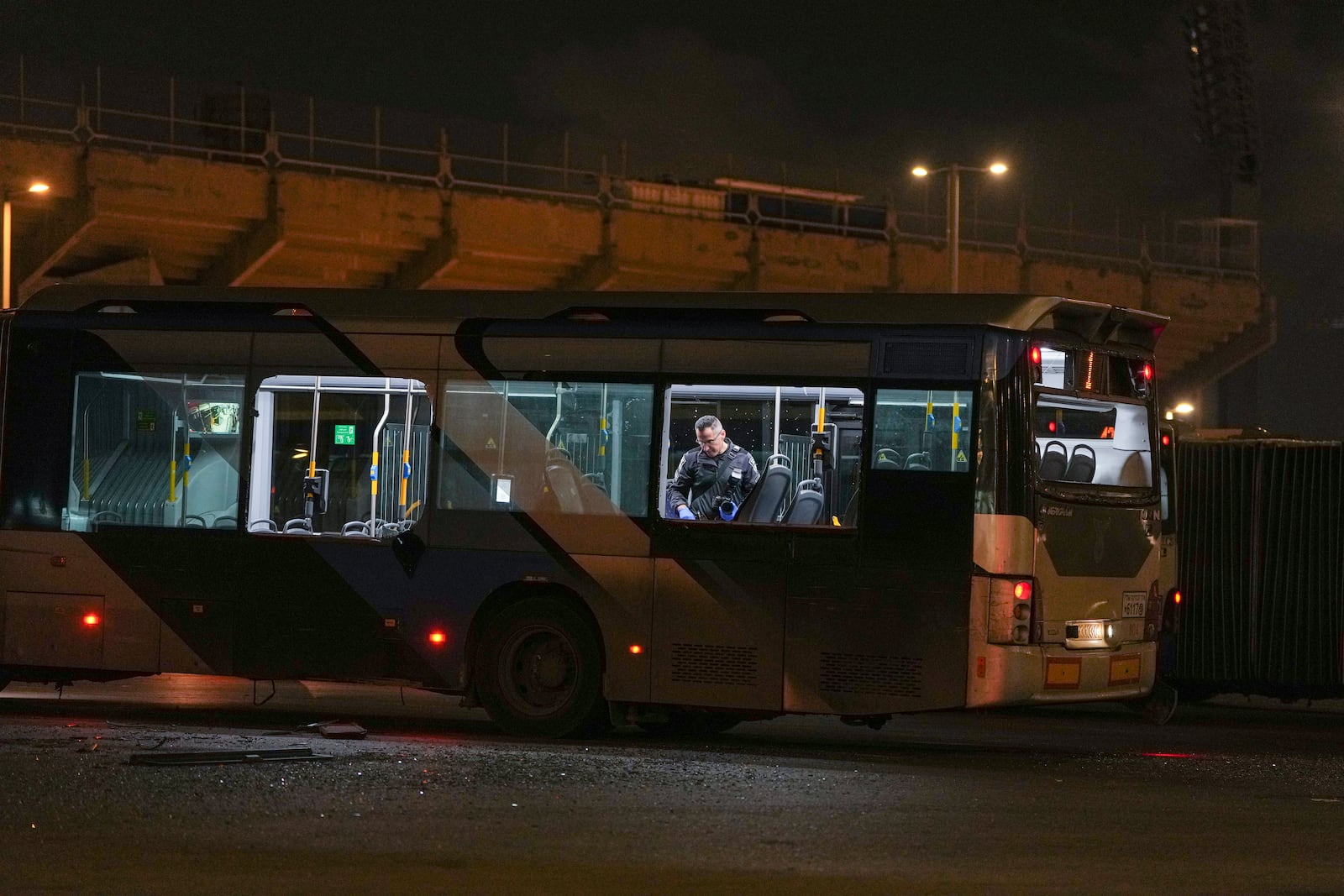 An Israeli police officer inspect the scene where police have reported a series of explosions on buses in what they said appeared to be a militant attack in Bat Yam, central Israel, Thursday Feb. 20, 2025. No injuries were reported. (AP Photo/Ohad Zwigenberg)