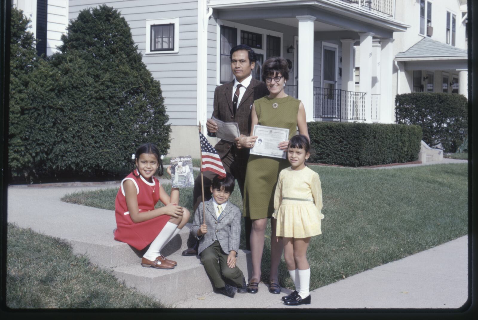 A family photo taken the day Madeline Iseli's parents were officially naturalized.  They're holding their naturalization certificates in front of their home in the Five Oaks neighborhood of Dayton. Iseli is pictured on the left. (CONTRIBUTED)