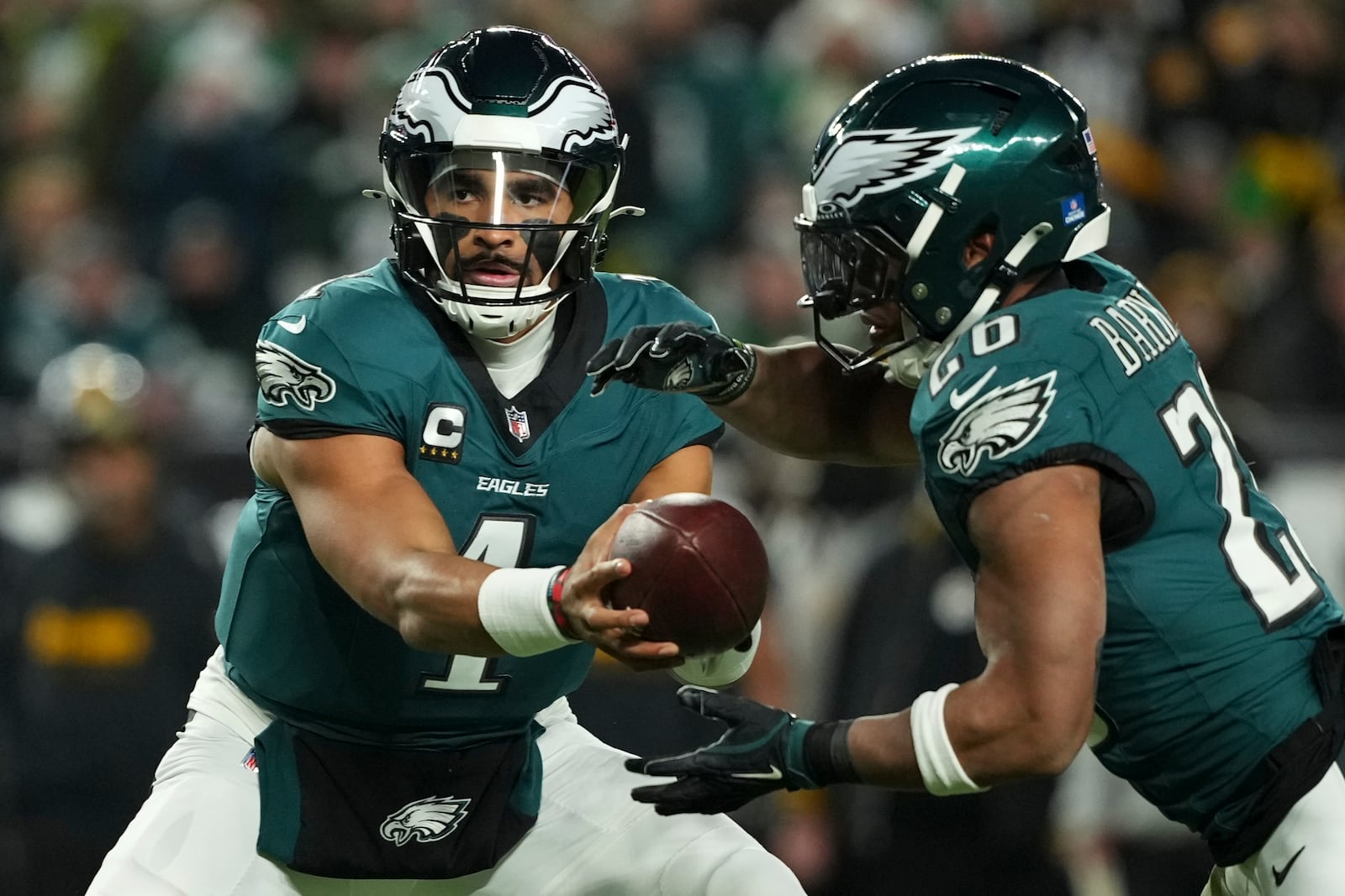 Philadelphia Eagles quarterback Jalen Hurts (1) hands off the ball to Philadelphia Eagles running back Saquon Barkley (26) during the first half of an NFL football game against the Pittsburgh Steelers on Sunday, Dec. 15, 2024, in Philadelphia. (AP Photo/Matt Slocum)