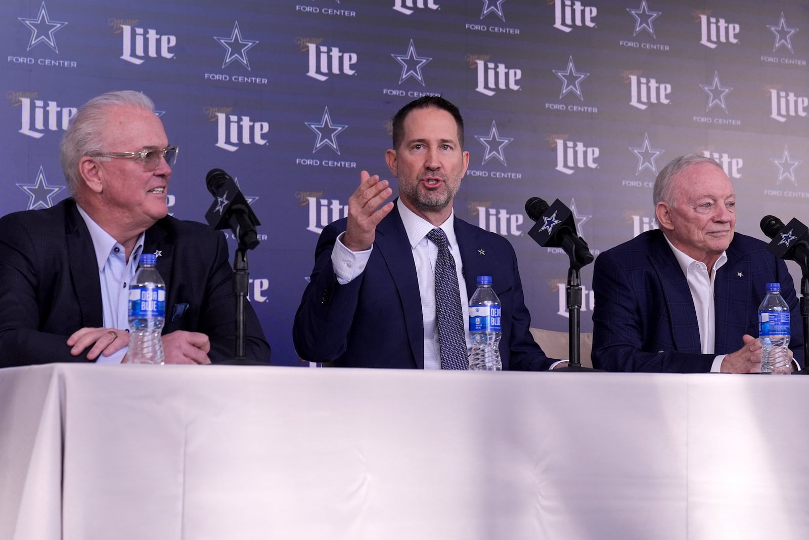 Brian Schottenheimer, center, makes comments as Dallas Cowboys Chief Operating Officer Stephen Jones, left, and team owner Jerry Jones, right, listen during a news conference where Schottenheimer was introduced as the new head coach at the team's headquarters in Frisco, Texas, Monday, Jan. 27, 2025. (AP Photo/Tony Gutierrez)