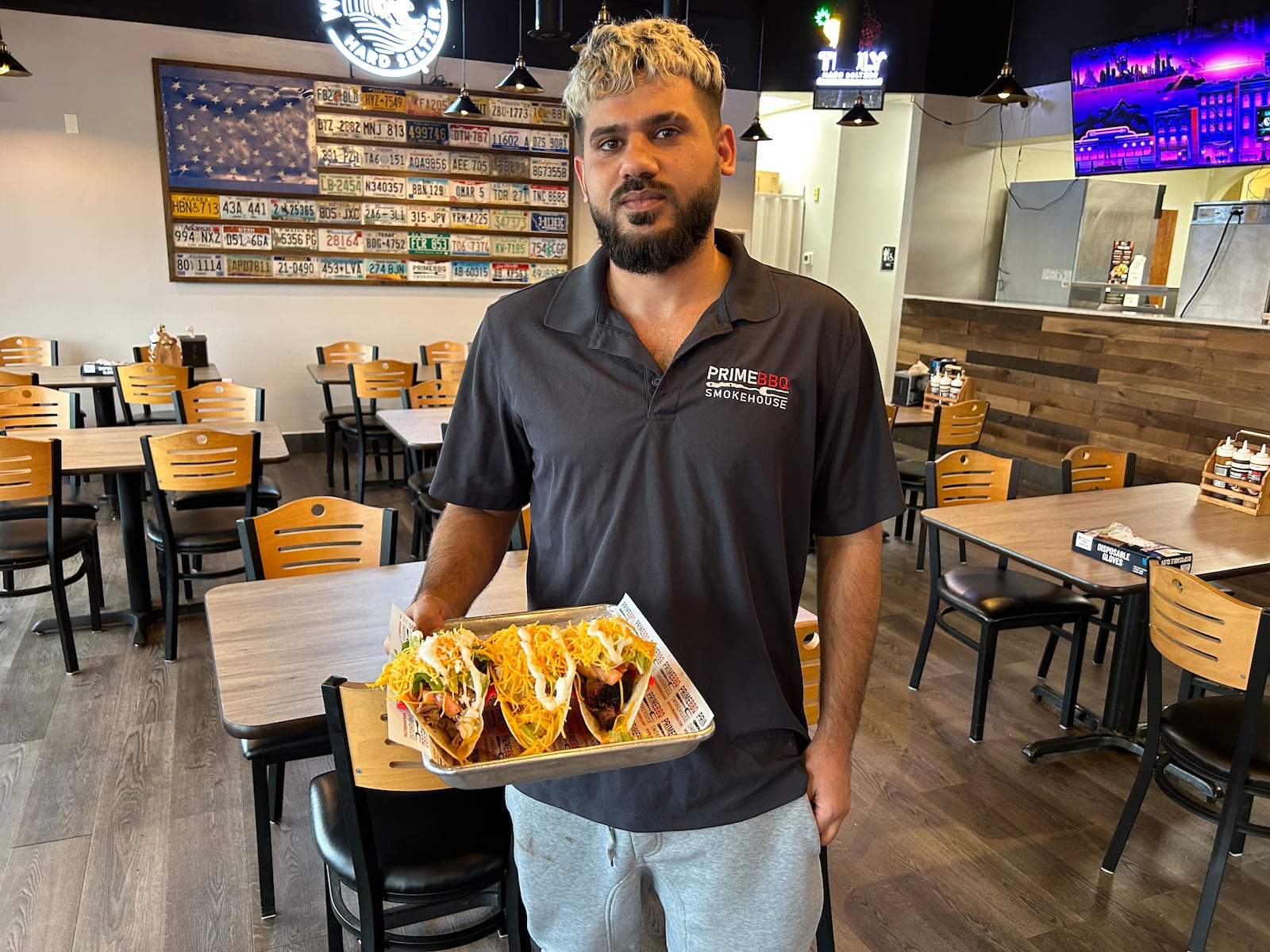 Nawaf Nayyef from Prime BBQ Smokehouse in Monroe delivers a plate of tacos to a customer. The restaurant has added to its menu, including three tacos on Tuesdays for $8.99. RICK McCRABB/STAFF