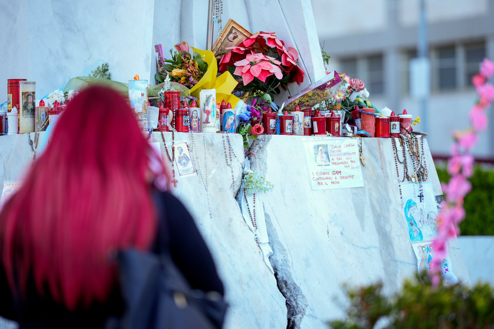 People pray for Pope Francis in front of the Agostino Gemelli Polyclinic, in Rome, Tuesday, March 18, 2025, where the Pontiff is hospitalized since Feb. 14. (AP Photo/Andrew Medichini)