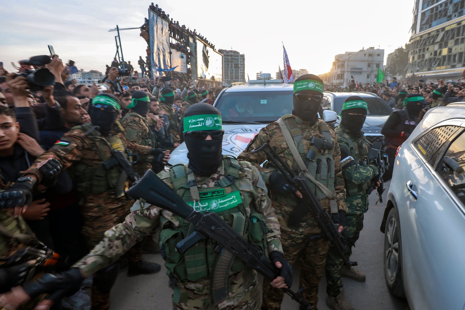 Hamas fighters escort a Red Cross vehicle to collect Israeli hostages released after a ceasefire agreement between Israel and Hamas took effect, in Gaza City Sunday, Jan. 19, 2025. (AP Photo/Abed Hajjar)