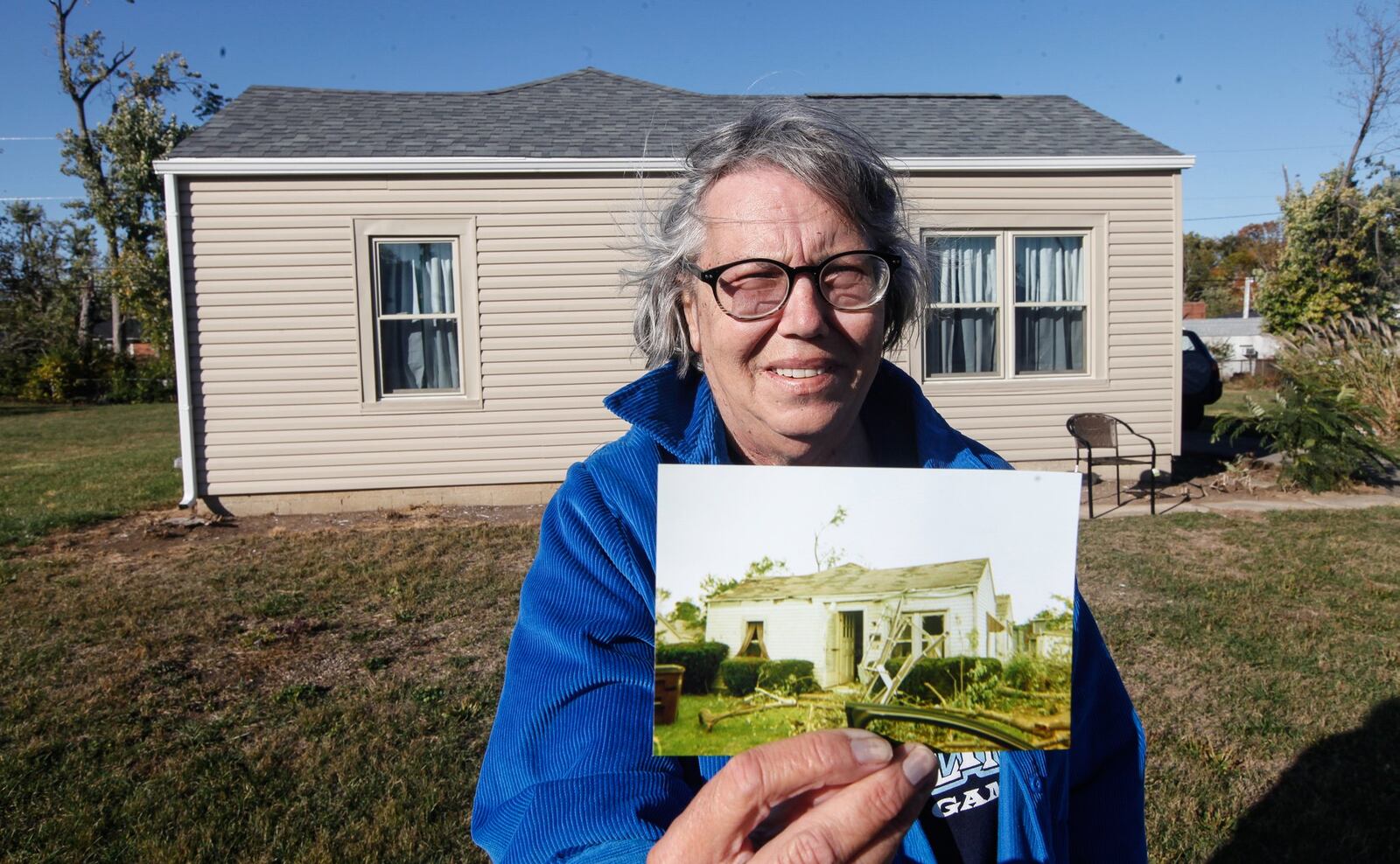 Pattie Meyer shows a photo of her Harrison Twp. home on Swallow Drive just after the tornado. It has since been repaired. CHRIS STEWART / STAFF