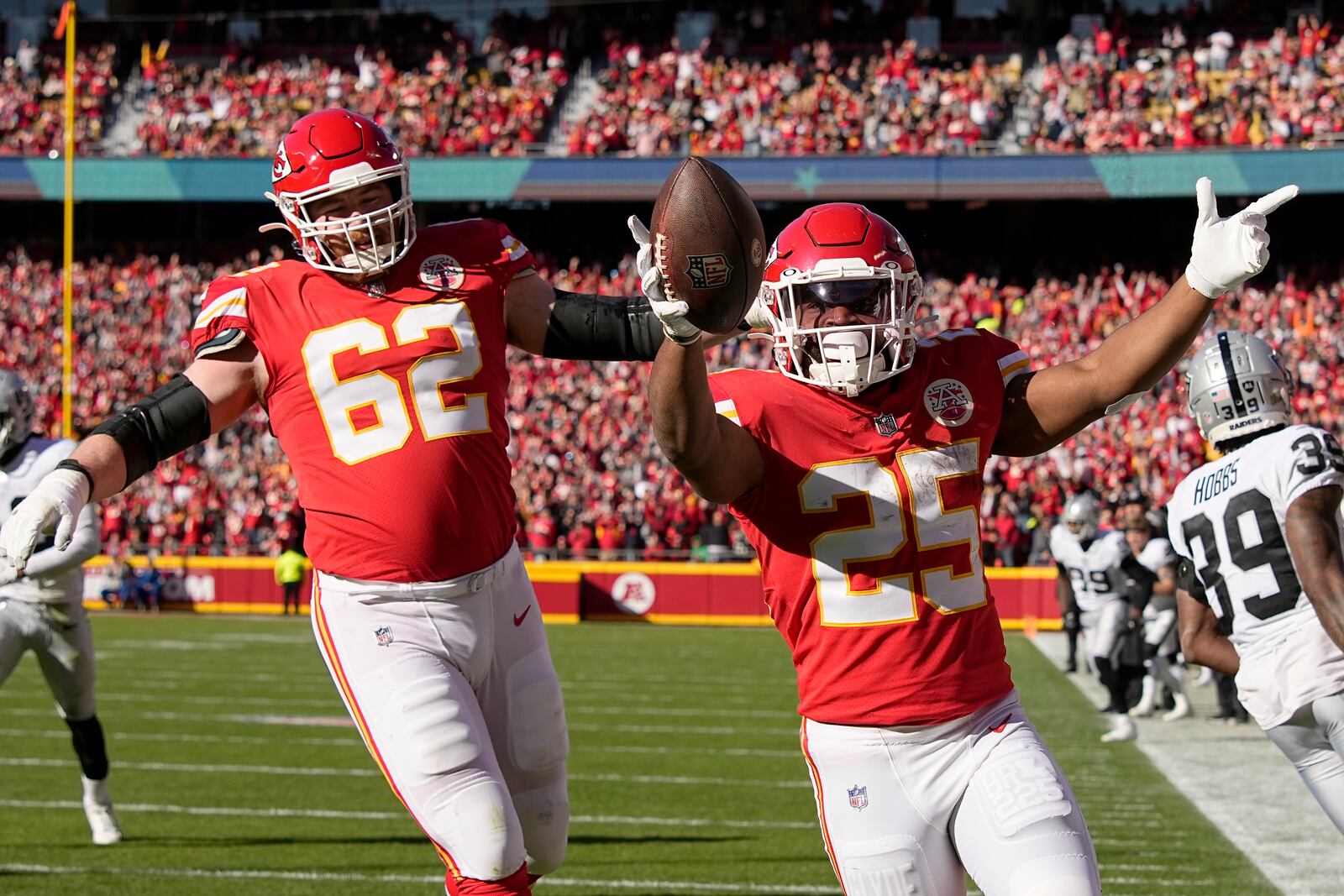 Kansas City Chiefs running back Clyde Edwards-Helaire (25) celebrates after scoring on a touchdown run as teammate Joe Thuney (62) watches during the first half of an NFL football game against the Las Vegas Raiders Sunday, Dec. 12, 2021, in Kansas City, Mo. (AP Photo/Charlie Riedel)