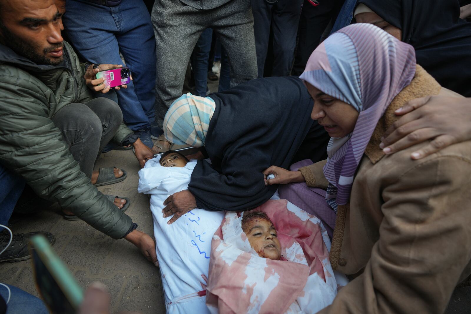 Areej al Qadi right mourns over the bodies of her three children before their funeral in Deir al-Balah, Gaza Strip, Thursday Nov. 21, 2024. Seven-year-old Hamza, his five-year-old brother Abdelaziz, and his four-year-old sister Laila Hassan were among 9 people killed by an Israeli strike in Khan Younis on Wednesday. Palestinian health officials say the death toll in the Gaza Strip from the 13-month-old war between Israel and Hamas has surpassed 44,000. (AP Photo/Abdel Kareem Hana)