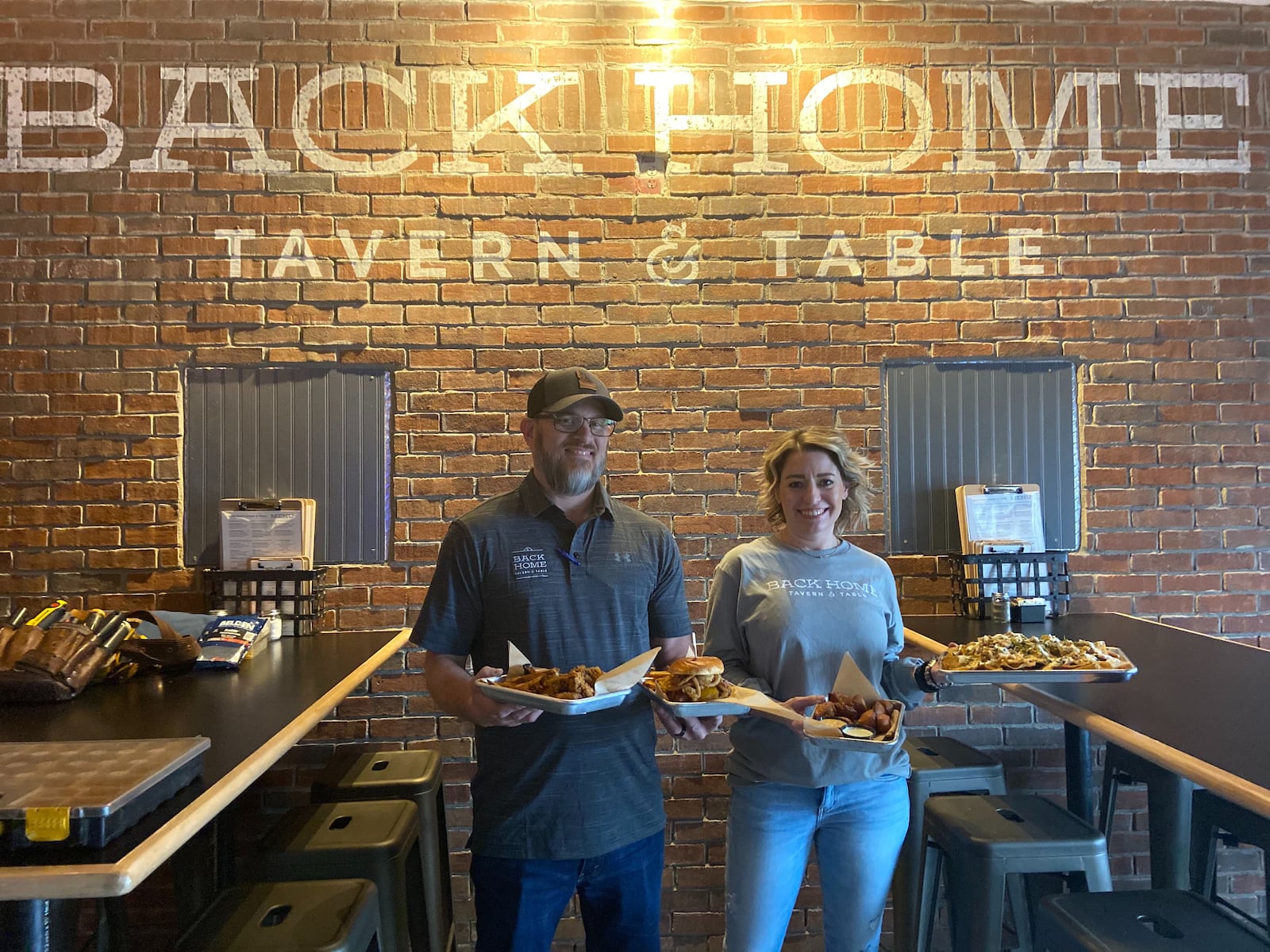 Two of the restaurant's owners, Jason and Michelle Dobbin are pictured here holding some of Back Home Tavern & Table's specialty dishes. ALLEGRA CZERWINSKI / STAFF PHOTO