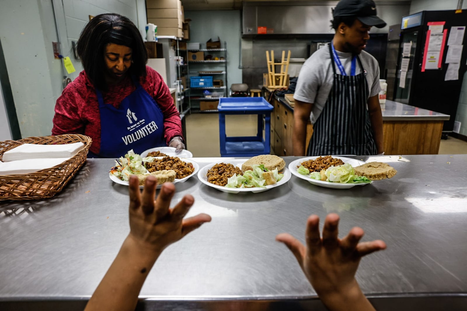 Volunteers Terrie Veal, left, and DeLeon Clay serve dinner to a boy at the St. Vincent de Paul Shelter for Women and Families on Apple Street in Dayton. JIM NOELKER/STAFF