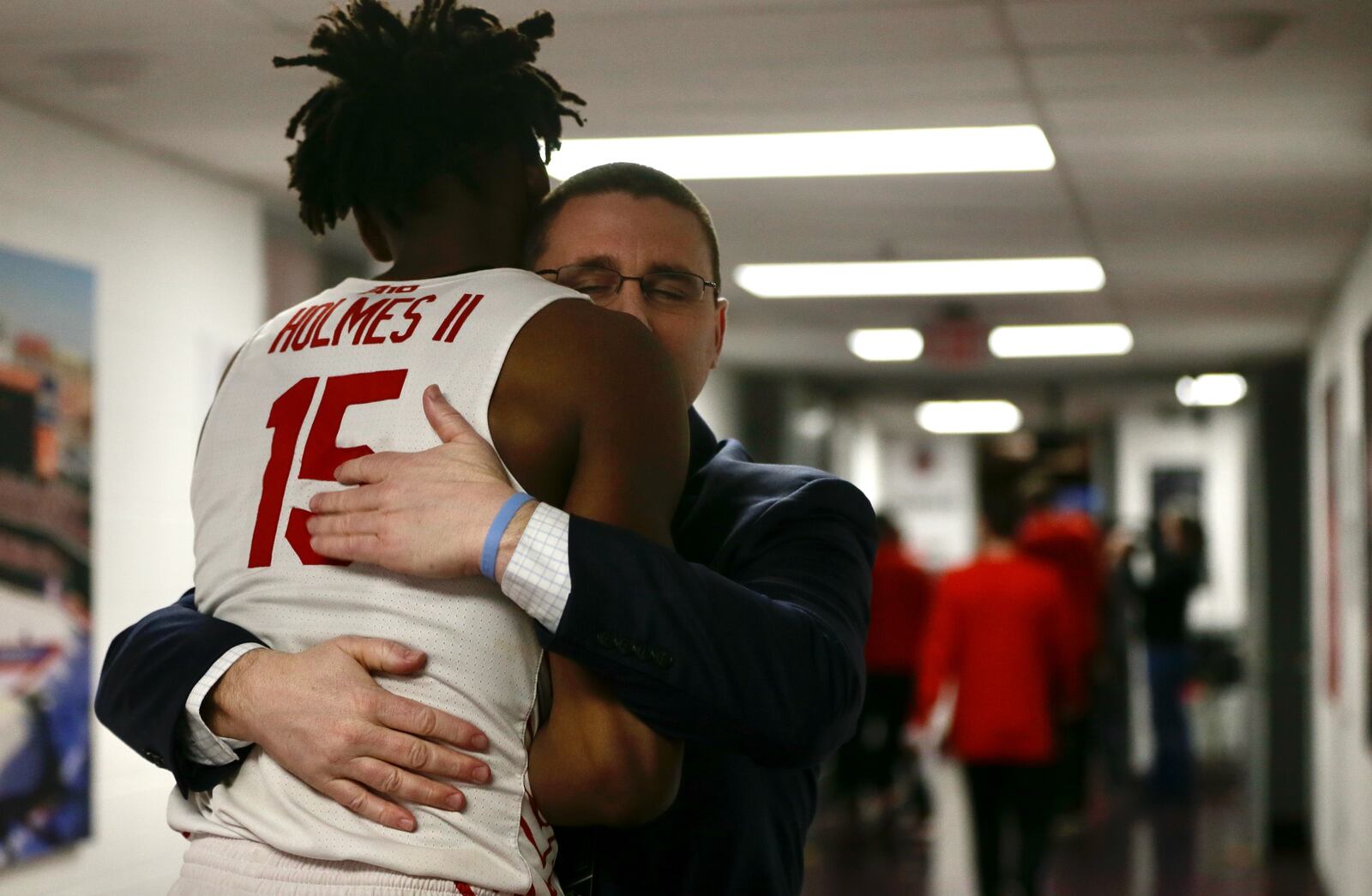 Dayton Athletic Director Neil Sullivan hugs DaRon Holmes II after a victory against Massachusetts on Friday, March 11, 2022, in the quarterfinals of the Atlantic 10 Conference tournament at Capital One Arena in Washington, D.C. David Jablonski/Staff