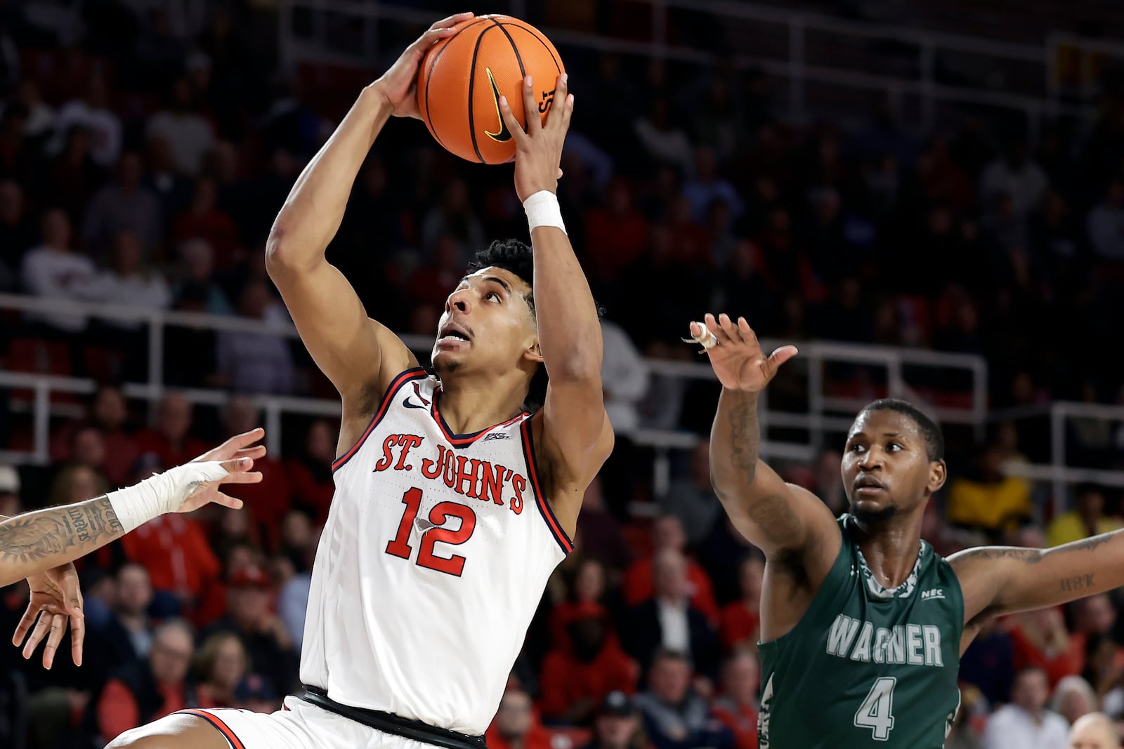 St. John's guard RJ Luis Jr. (12) drives to the basket past Wagner forward Tyje Kelton during the second half of an NCAA college basketball game Wednesday, Nov. 13, 2024, in New York. St. John's won 66-45. (AP Photo/Adam Hunger)