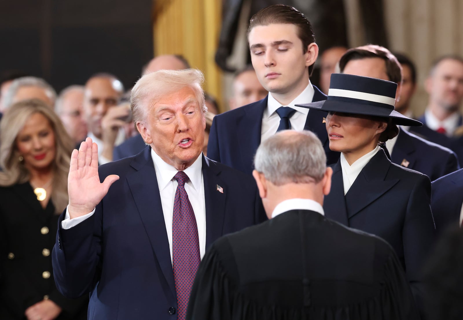 President-elect Donald Trump, from left, takes the oath of office as Barron Trump and Melania Trump watch at the 60th Presidential Inauguration in the Rotunda of the U.S. Capitol in Washington, Monday, Jan. 20, 2025. (Kevin Lamarque/Pool Photo via AP)