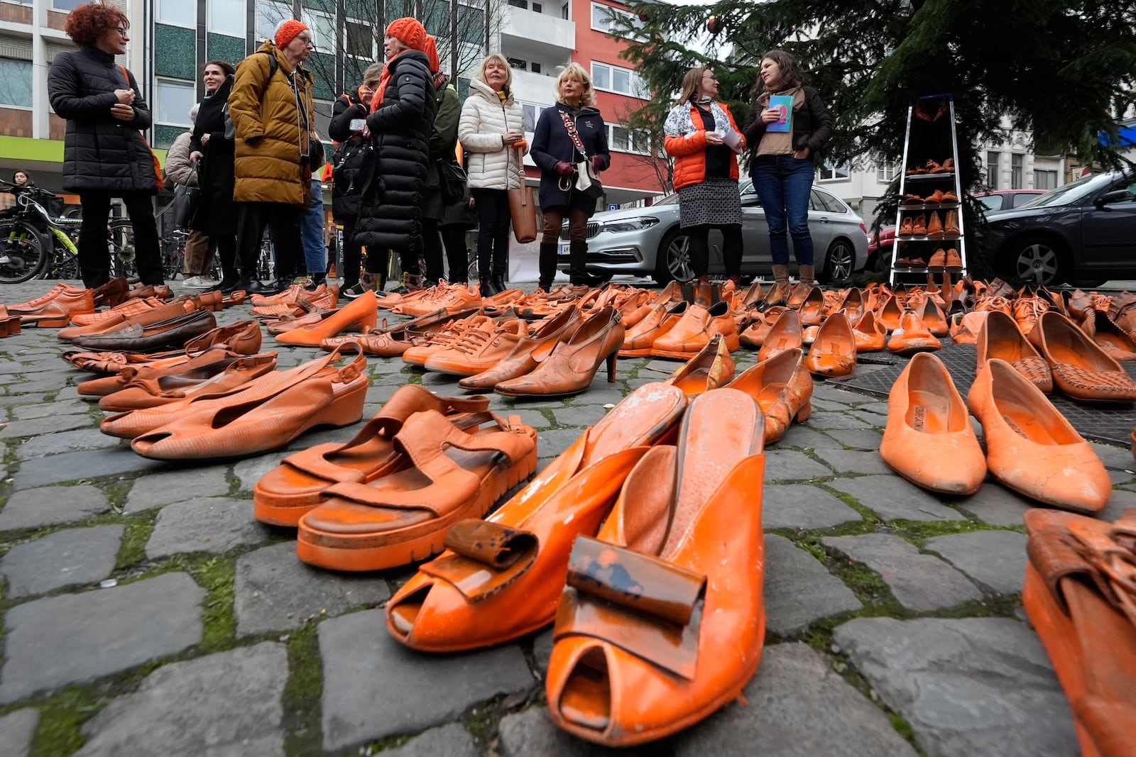 Women's rights activists set orange pair of shoes on the pavement for every attempted or successful killing of a woman by partner violence during the International Day for the Elimination of Violence Against Women, the start of the Orange Days in Cologne, Germany, Monday, Nov. 25, 2024. (AP Photo/Martin Meissner)