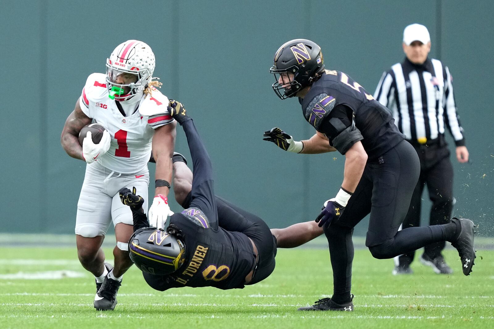 Ohio State running back Quinshon Judkins carries the ball as Northwestern defensive back Devin Turner (8) and linebacker Greyson Metz defend during the first half of an NCAA college football game at Wrigley Field on Saturday, Nov. 16, 2024, in Chicago. (AP Photo/Charles Rex Arbogast)