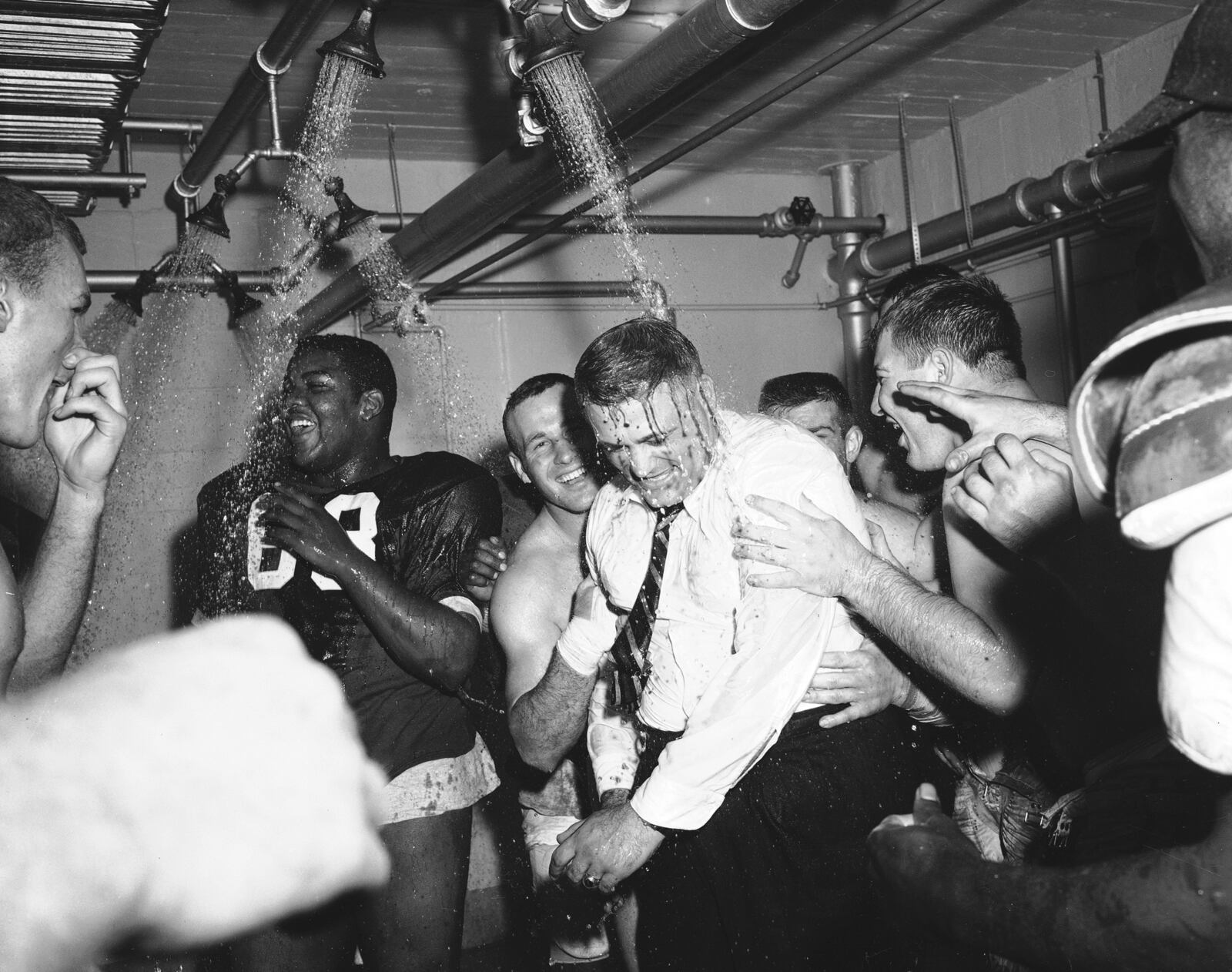 In this Nov. 16, 1957, file photo, Ohio State football coach Woody Hayes, center, gets a clothes-on dunking in the Ohio State dressing room shortly after Ohio State University won the Big Ten championship and clinched a Rose Bowl bid by defeating Iowa 17-13, in Columbus, Ohio.  (AP Photo/File)