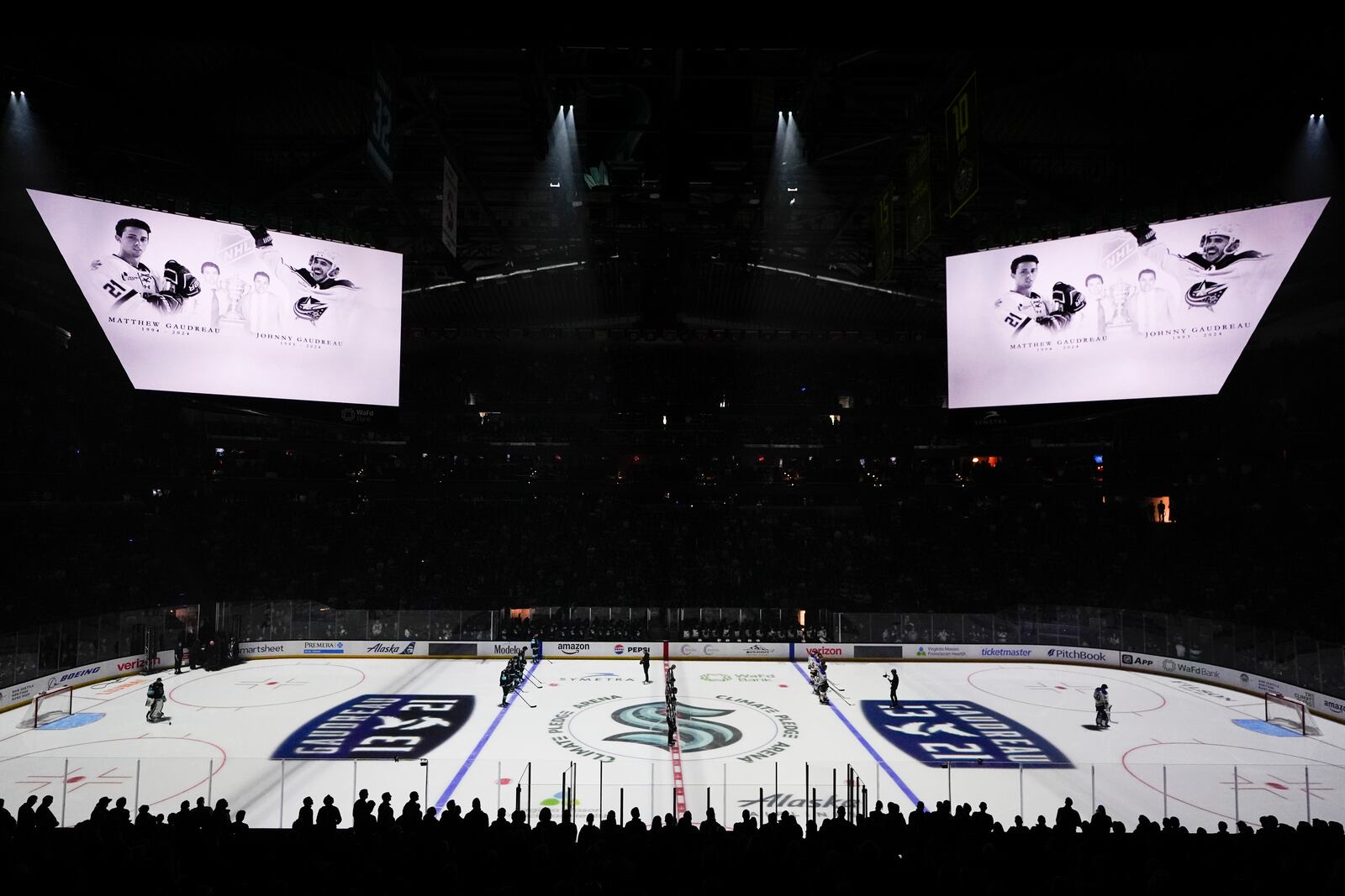 Seattle Kraken and St. Louis Blues players stand for a moment of silence for Columbus Blue Jackets player Johnny Gaudreau and his brother Matthew Gaudreau, who were killed by a driver in New Jersey in August, before an NHL hockey game, Tuesday, Oct. 8, 2024, in Seattle. (AP Photo/Lindsey Wasson)