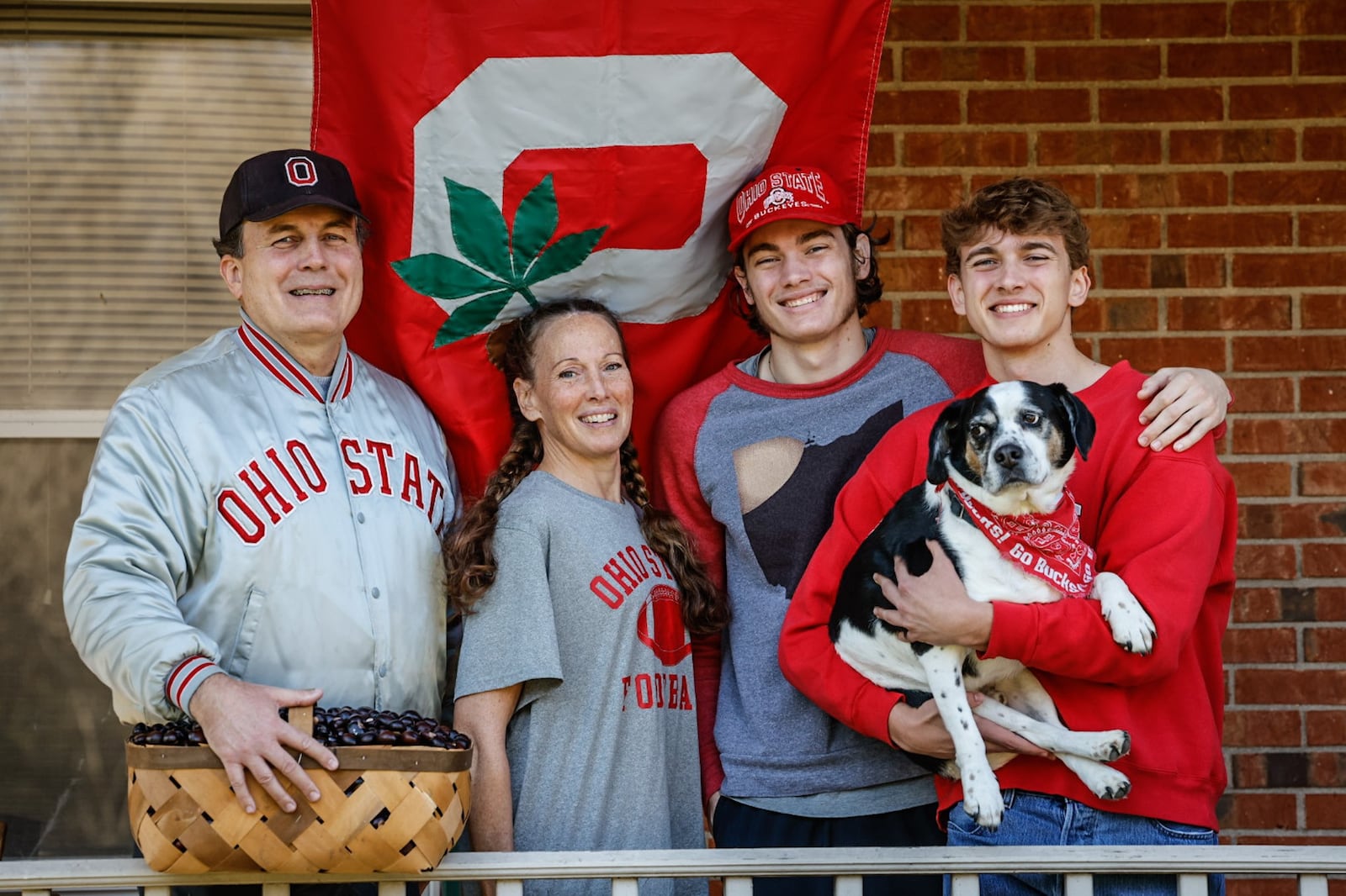 From left, John, Stacey, John and Jeff Koch will be rooting for The Ohio State Buckeyes at Ohio stadium in Columbus on Saturday.  John's wife, Stacey's family, who is from Michigan, will be cheering on the Michigan Wolverines. The family live in Springboro and their dogs name is J.J. JIM NOELKER/STAFF