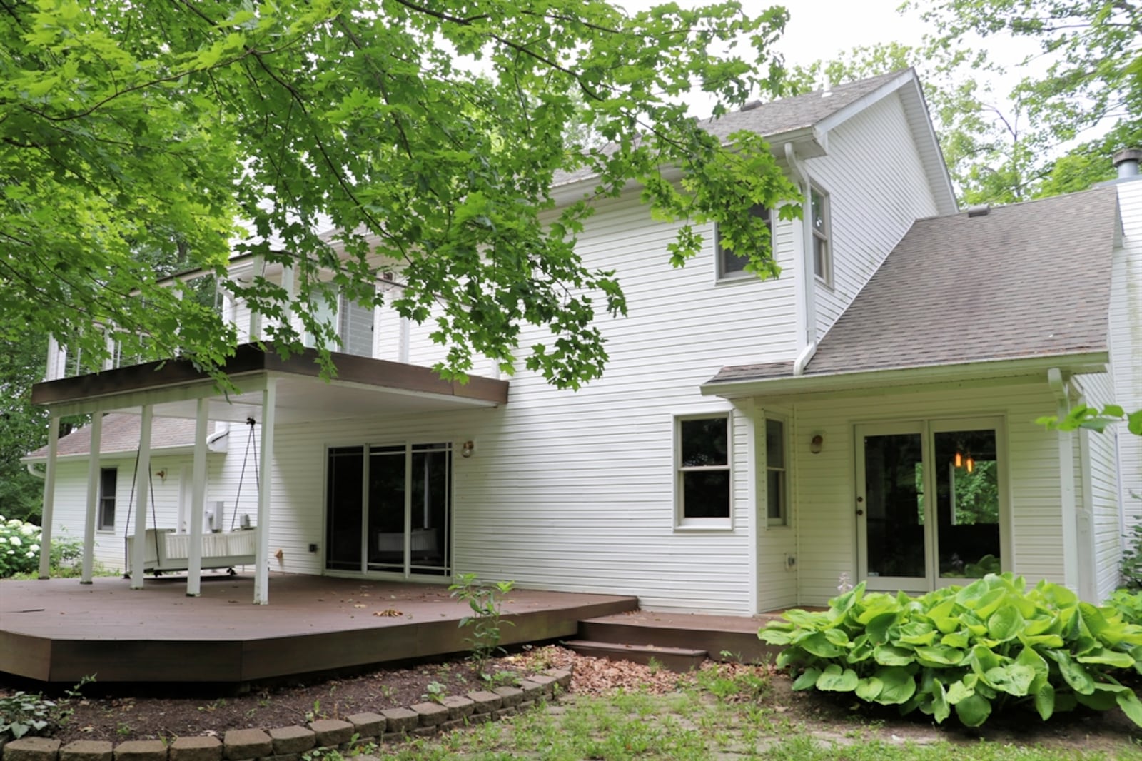 Triple patio doors open from the family room out to the covered deck, which has a custom-made porch swing and views of the wooded area of the property.