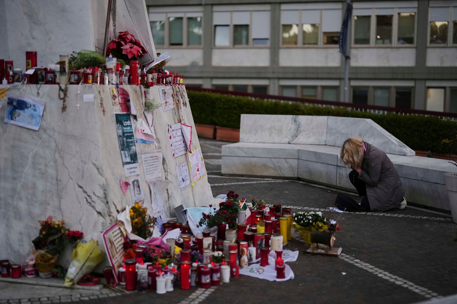 A woman prays next to the statue of Pope John Paul II, outside the Agostino Gemelli Polyclinic, where the Pope Francis is being treated for pneumonia, in Rome, Monday, March 10, 2025. (AP Photo/Francisco Seco)