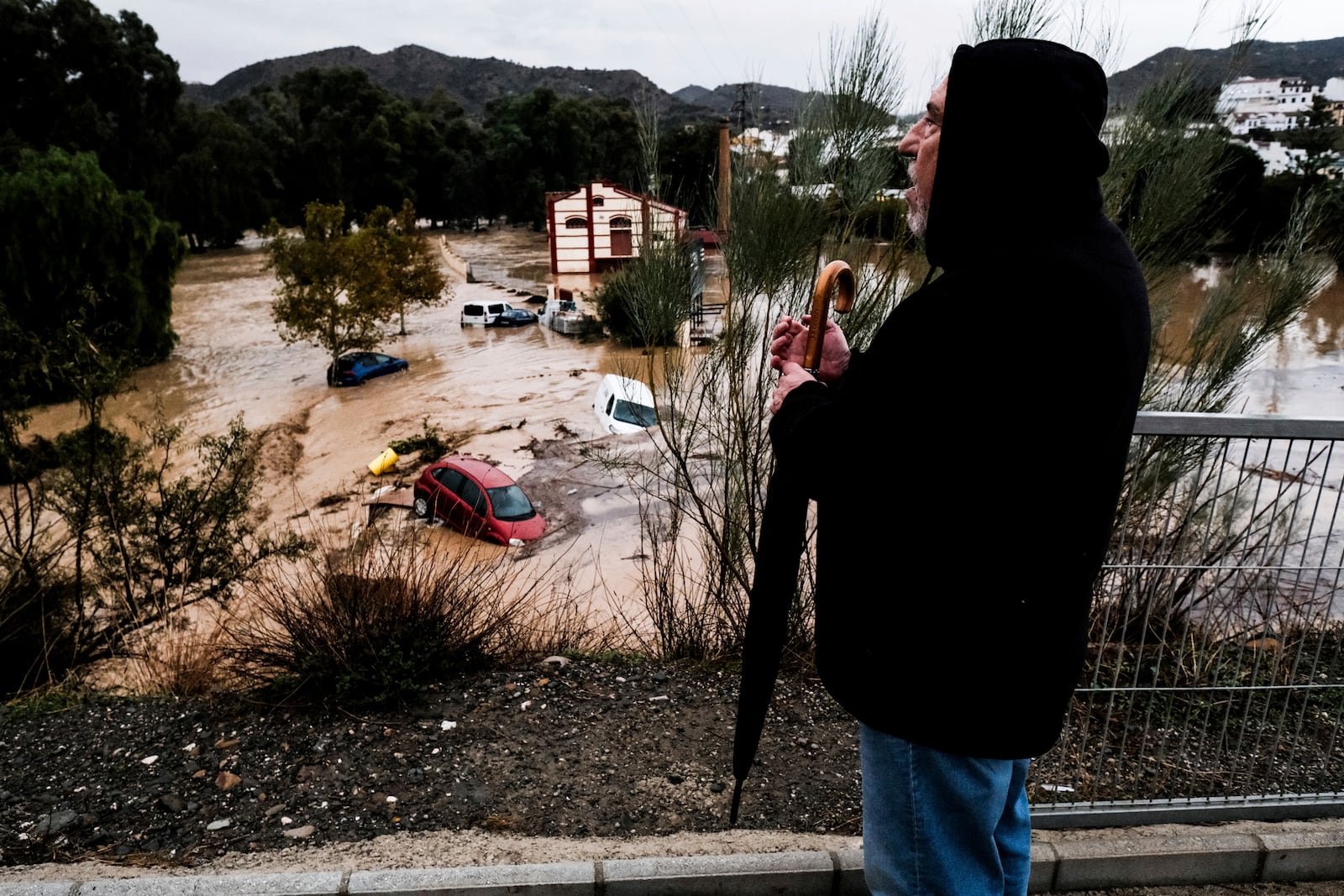 A man observes several cars being swept away by the water, after floods preceded by heavy rains caused the river to overflow its banks in the town of Alora, Malaga, Tuesday, Oct. 29, 2024. (AP Photo/Gregorio Marrero)